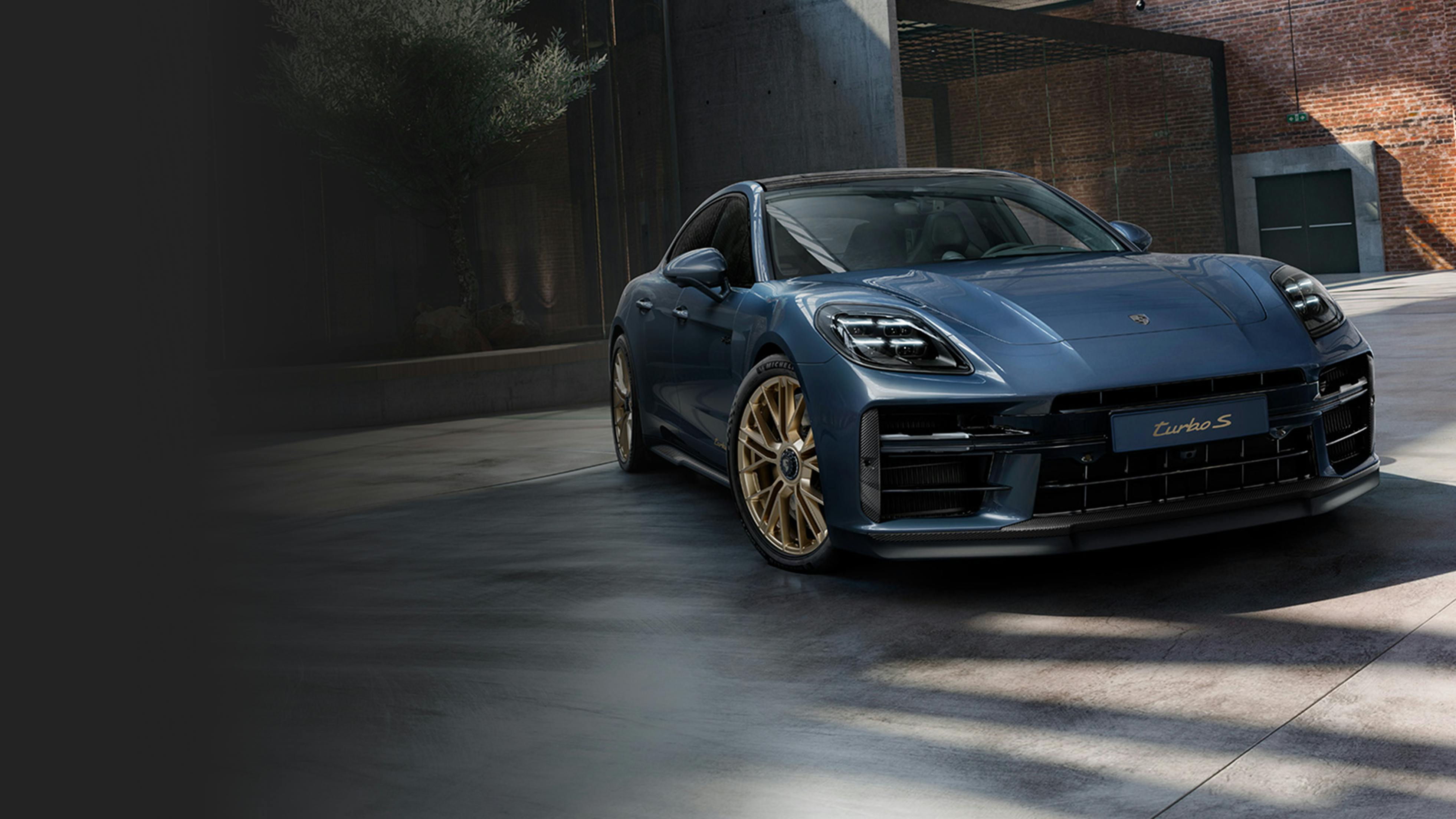 Front view of the front of the Porsche Exclusive Manufaktur Panamera Turbo S E-Hybrid in Yachting Blue Metallic with Aerokit Carbon.