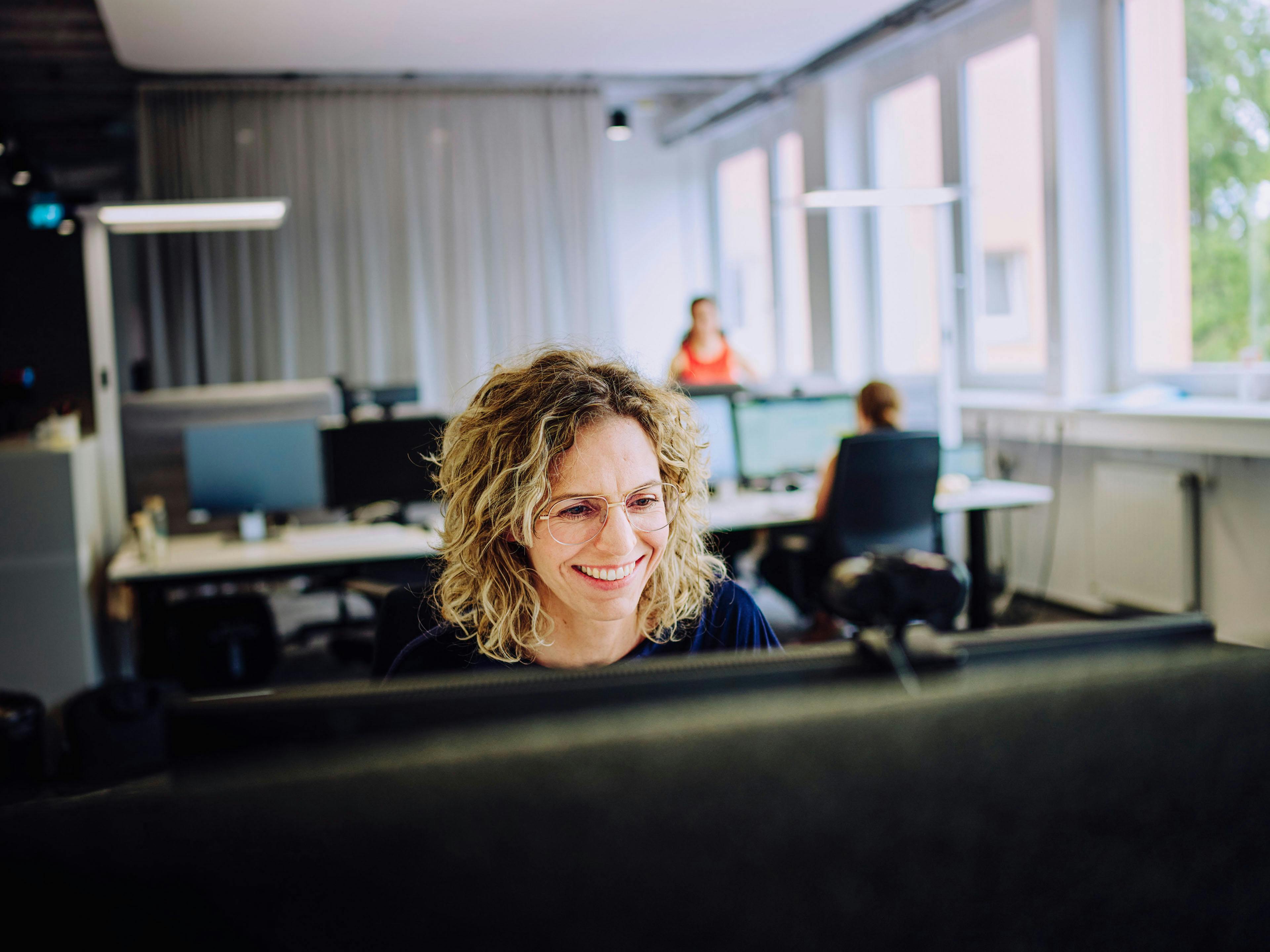 A doctoral student at Porsche smiles at her screen.