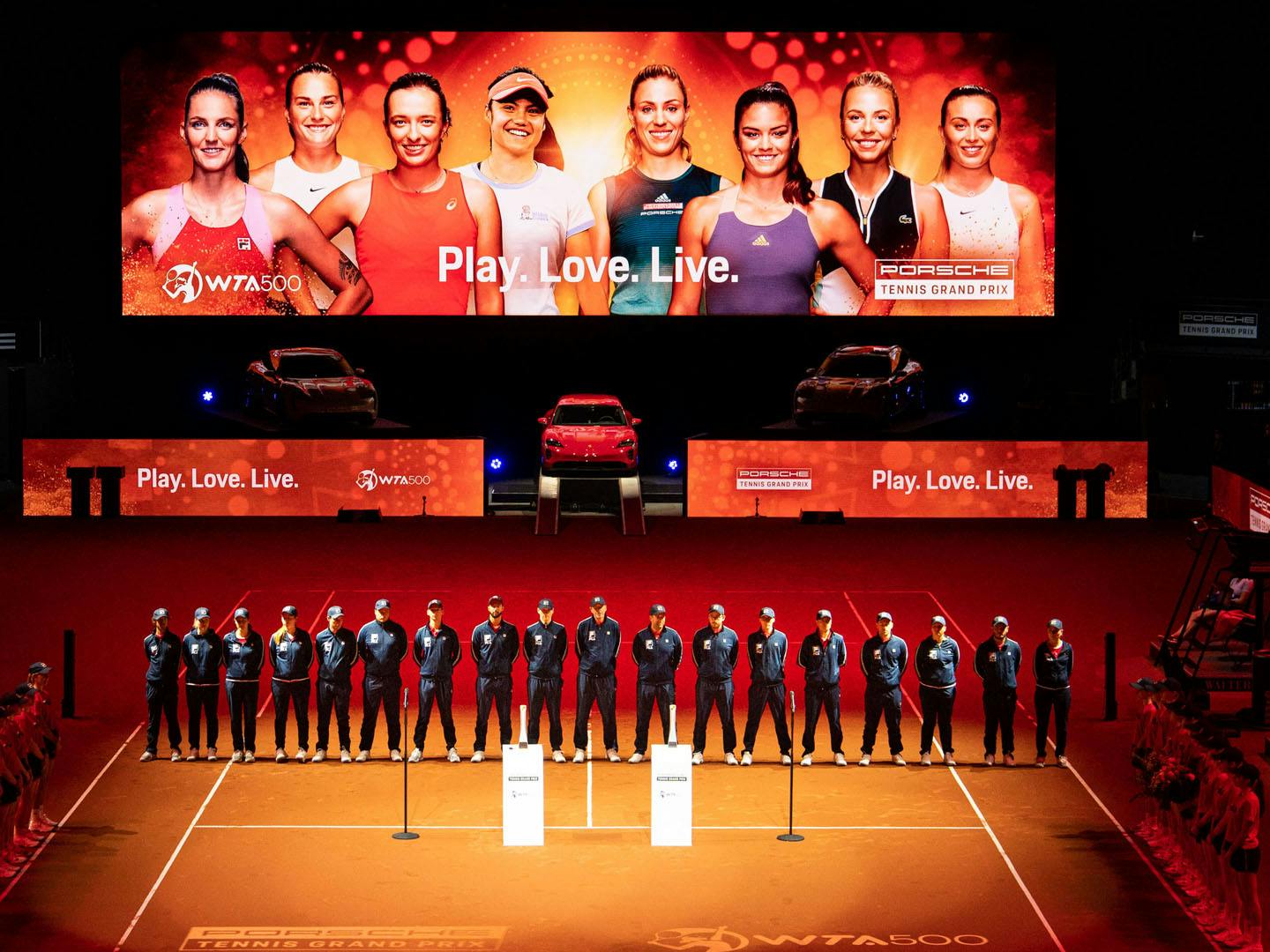 Deltagare uppradade på Porsche Tennis-event med en stor LED-skärm i bakgrunden.
