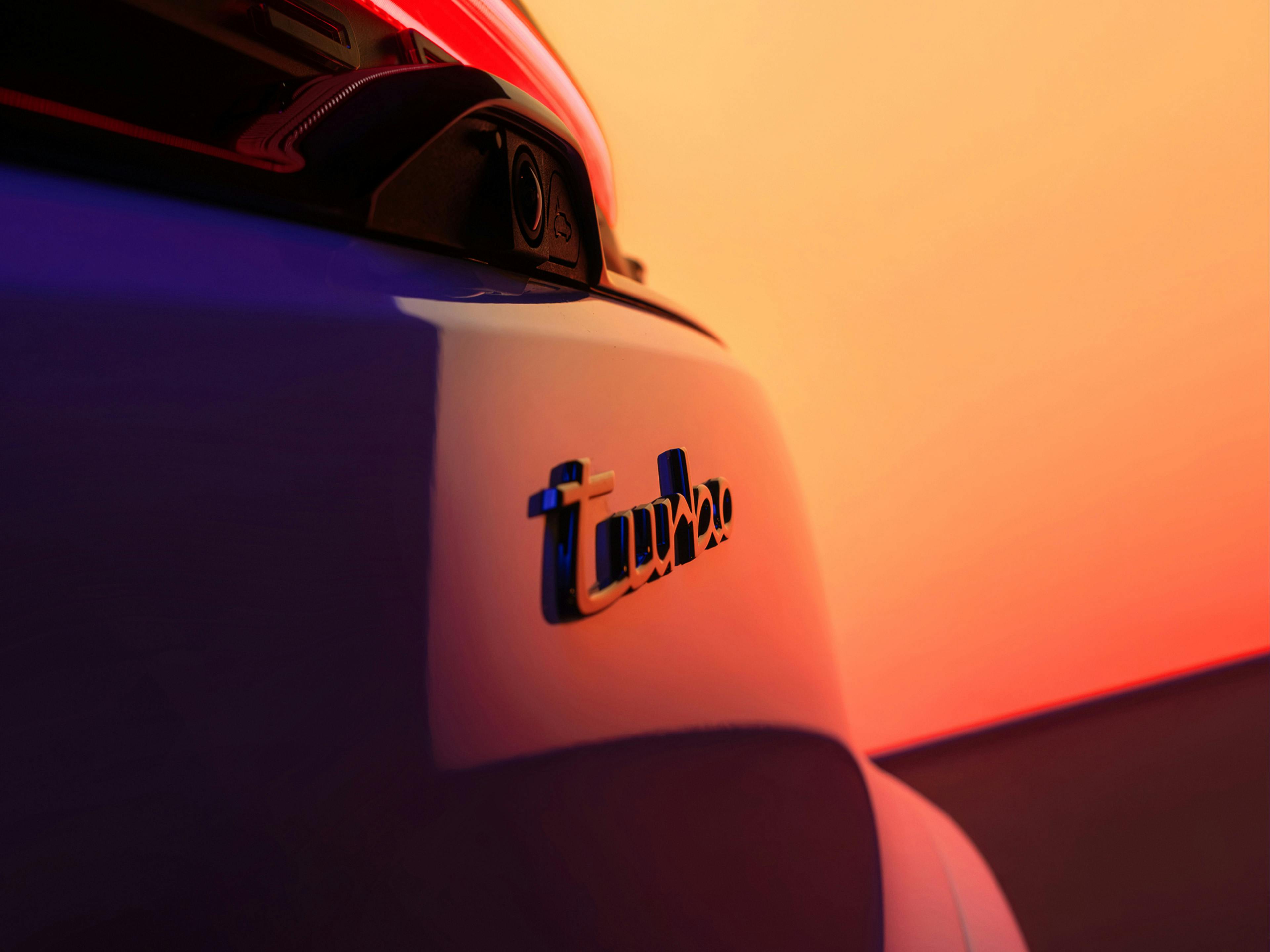 Porsche Macan rear turbo badge with vibrant studio lighting.