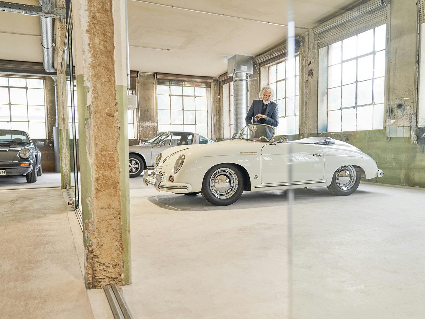 Een man loopt in een ruimte met verschillende Porsche classic modellen