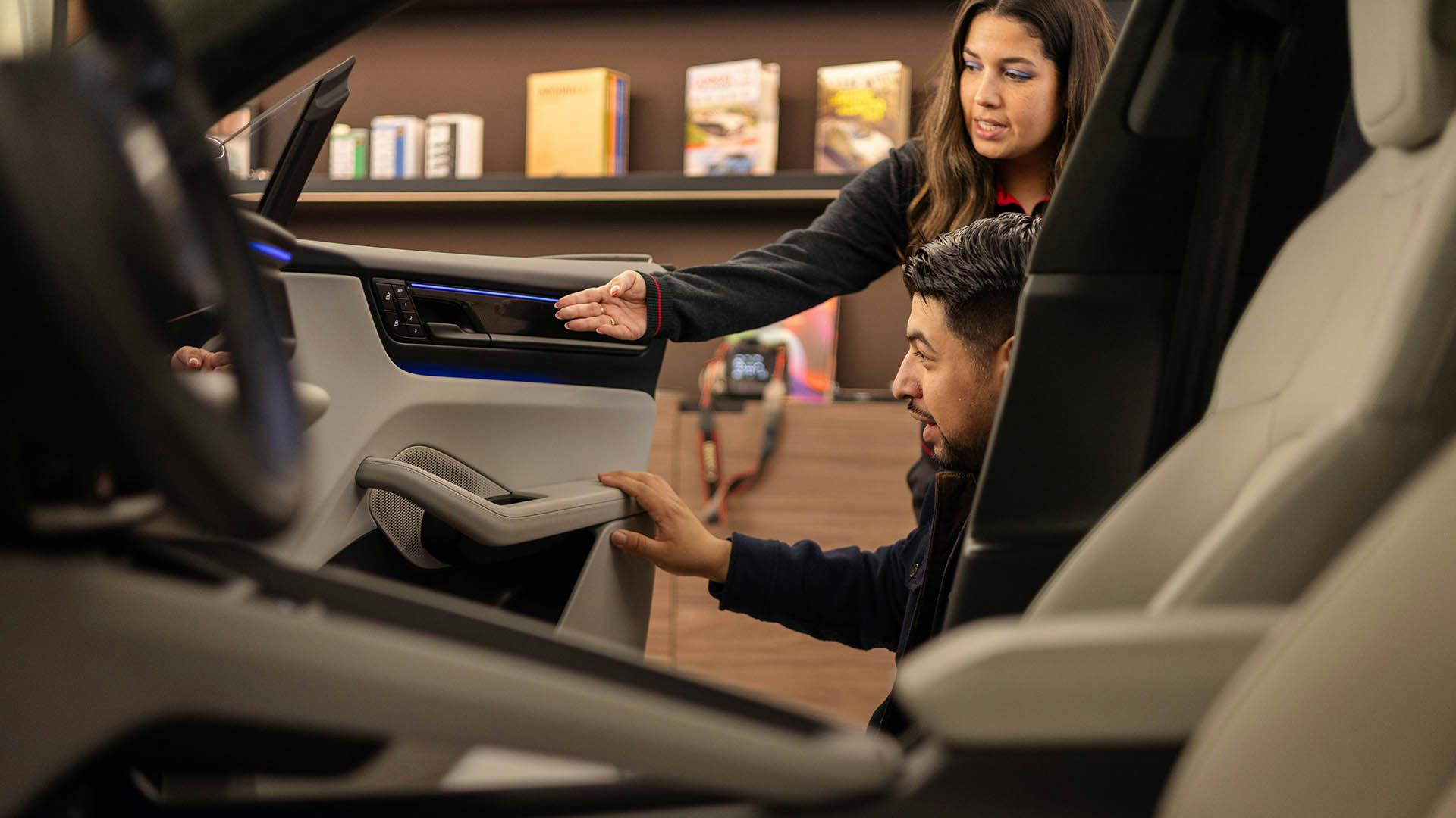 A man and woman inspecting the details of a car door panel. ​