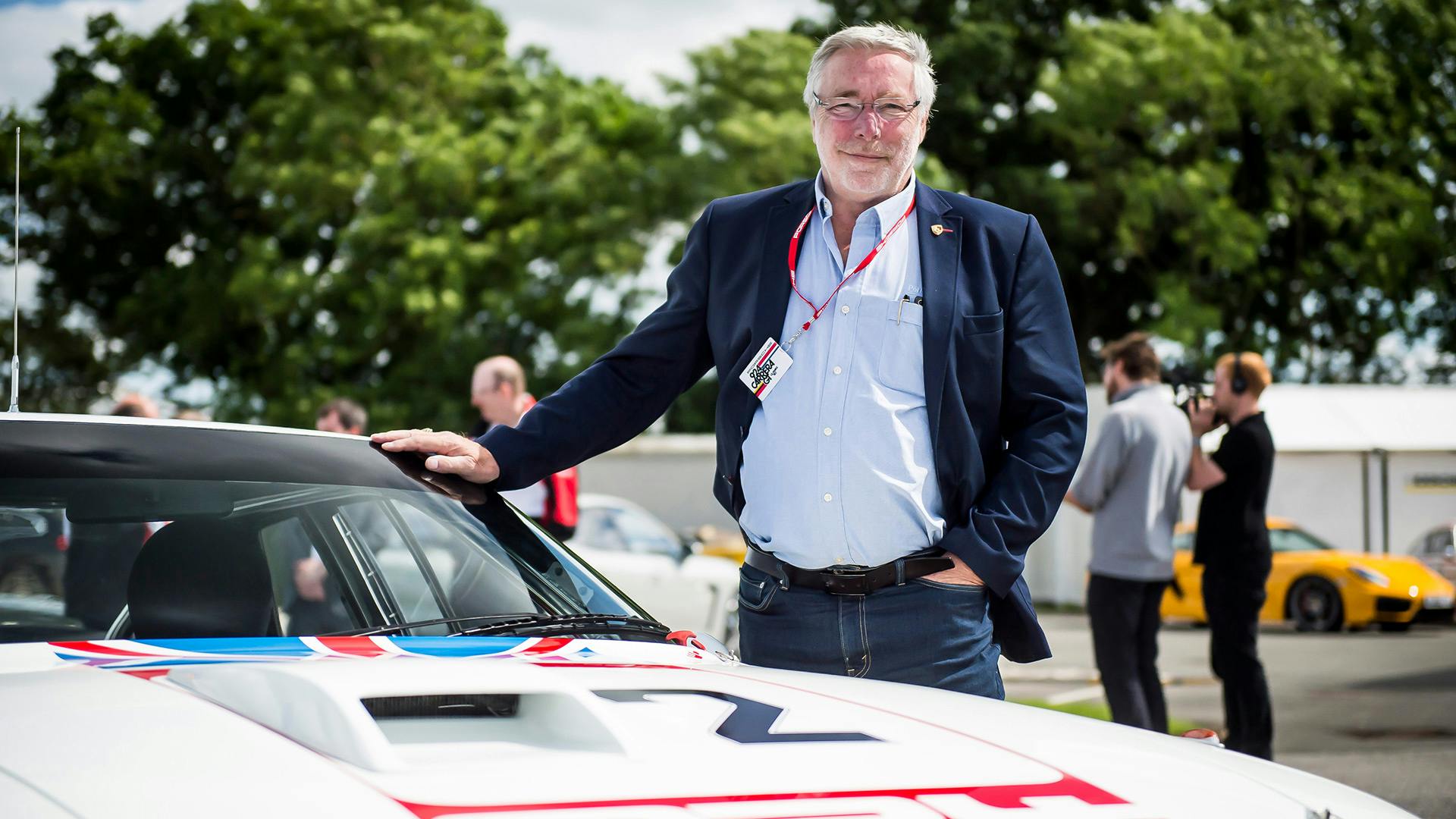 Man standing next to fully restored Porsche 924 GTP.