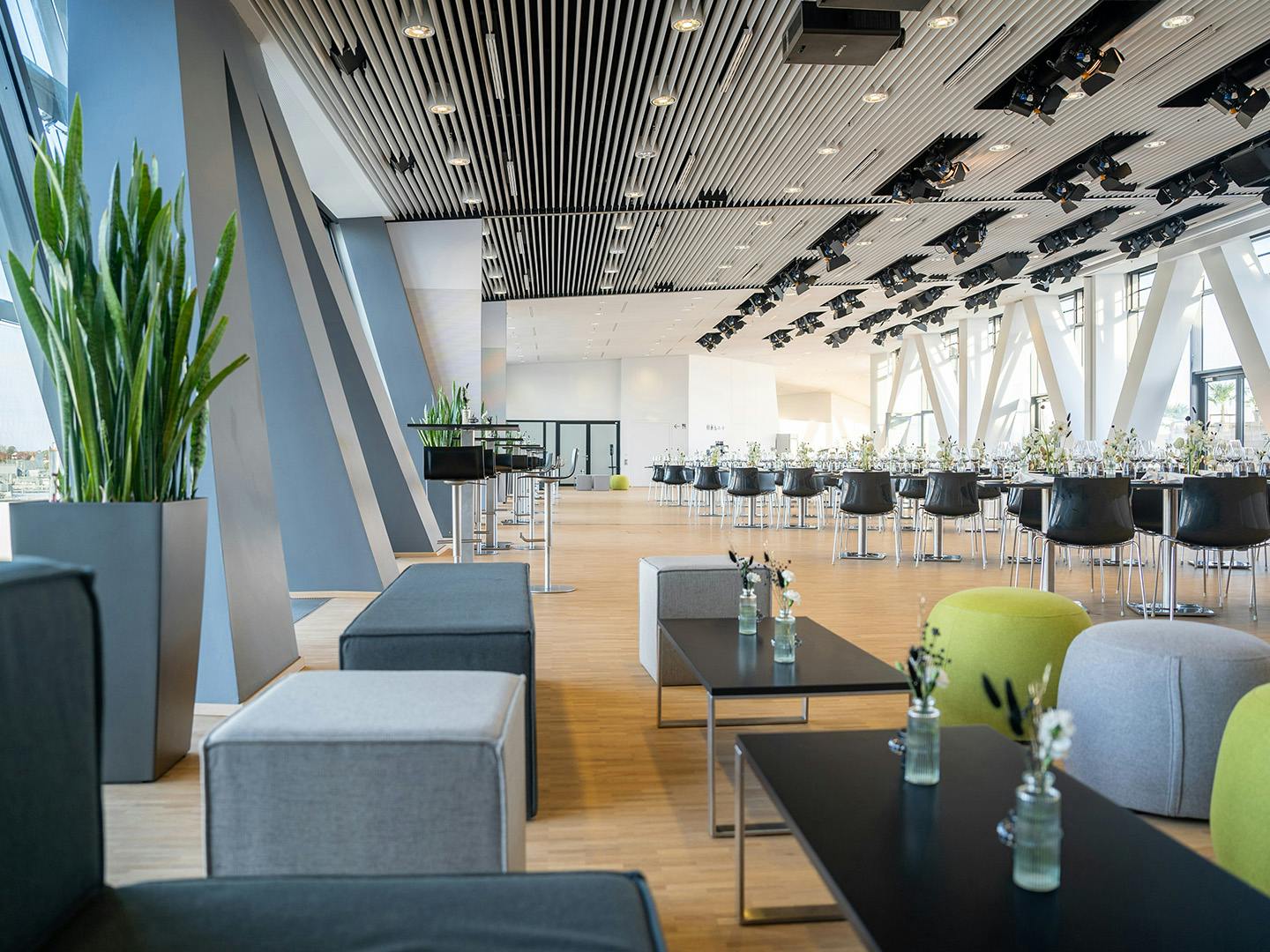 Eventraum im Porsche Museum mit weißen Tischreihen und Stühlen. Loungehocker laden zum Sitzen ein.