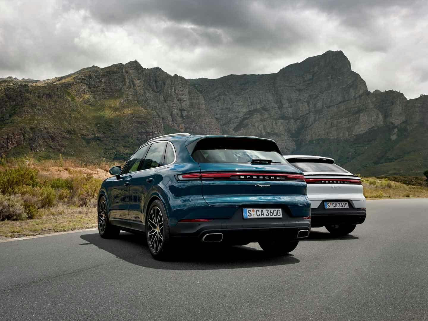 Två Porsche Cayenne parkerade framför ett berg.
