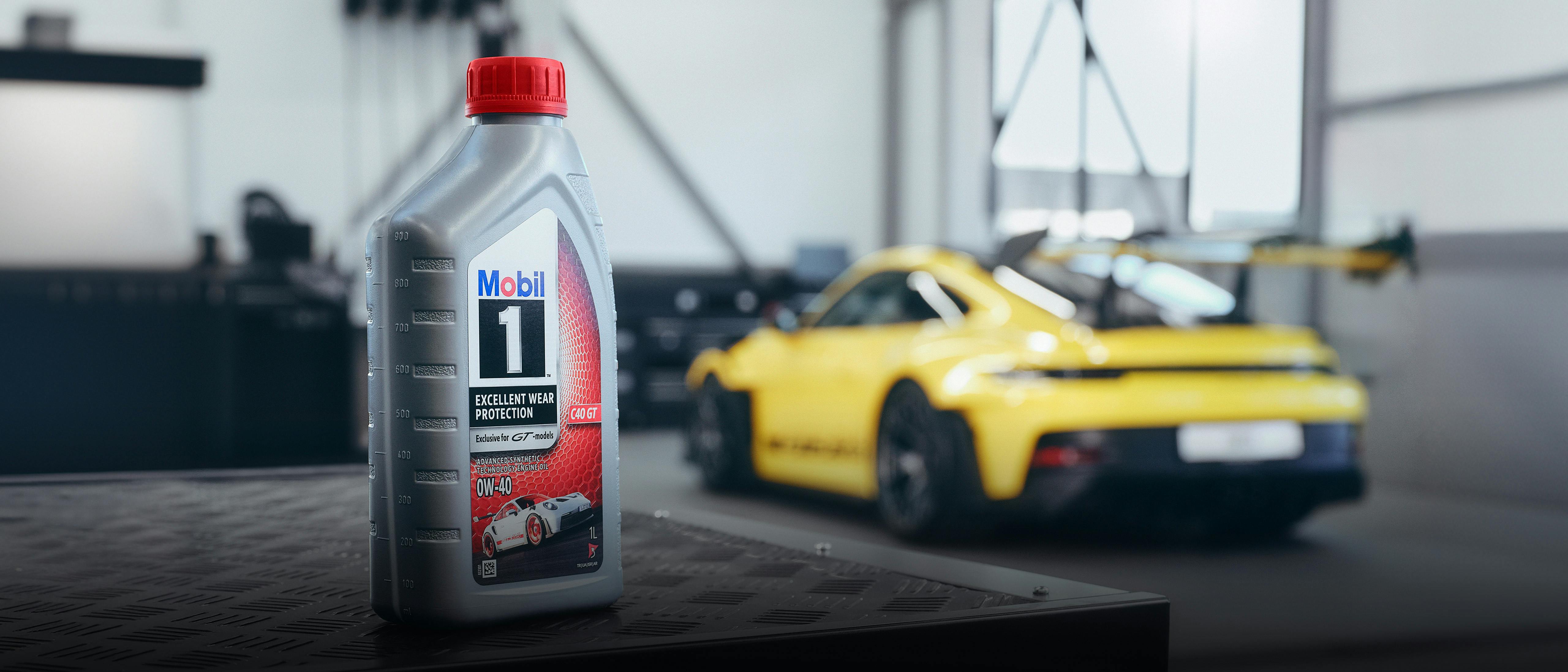 In the foreground is a Mobil 1 oil bottle. A Porsche 911 can be seen in the background.