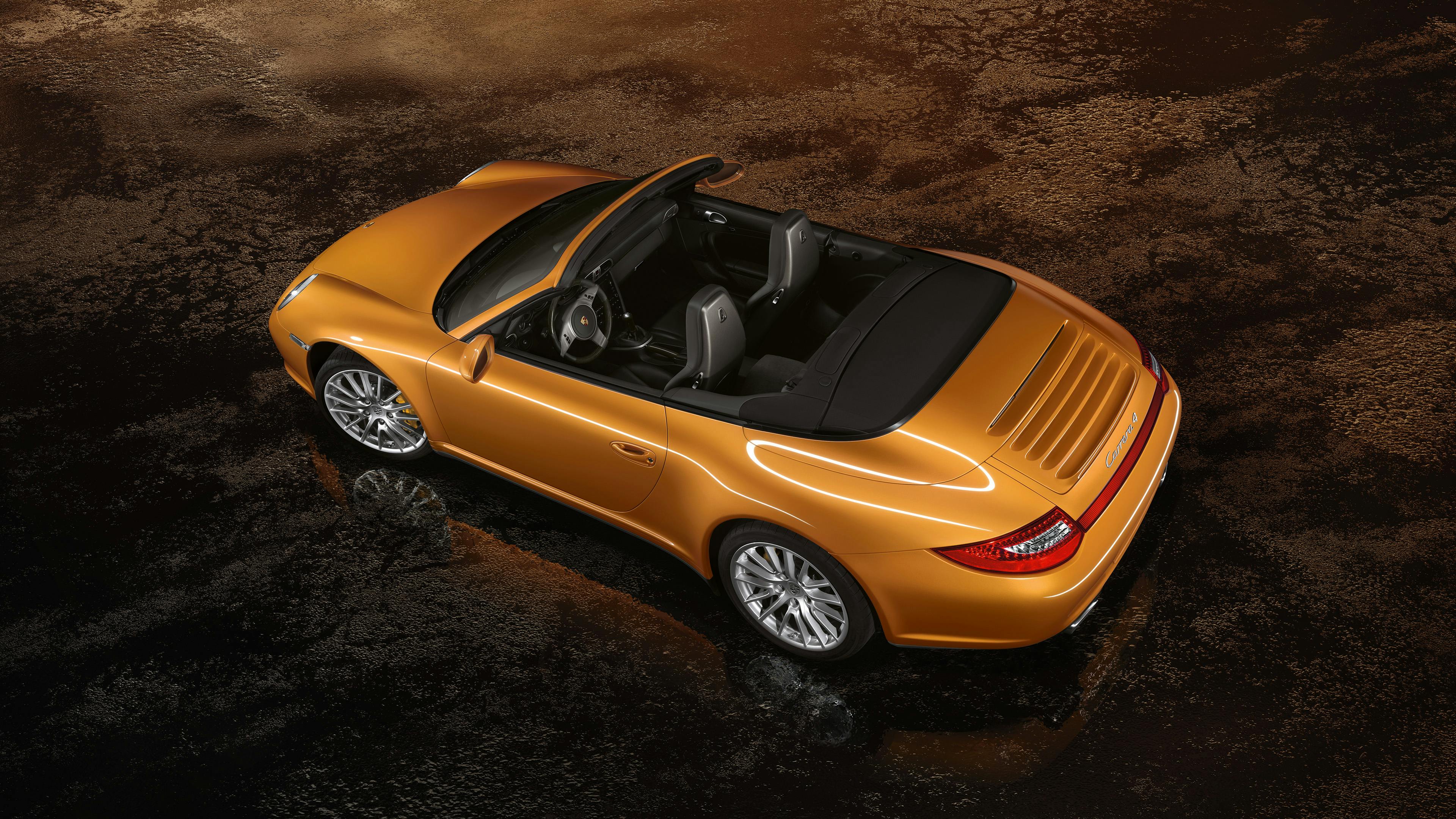 Studio shot of an orange 997 911 Carrera Cabriolet on brown carpet.