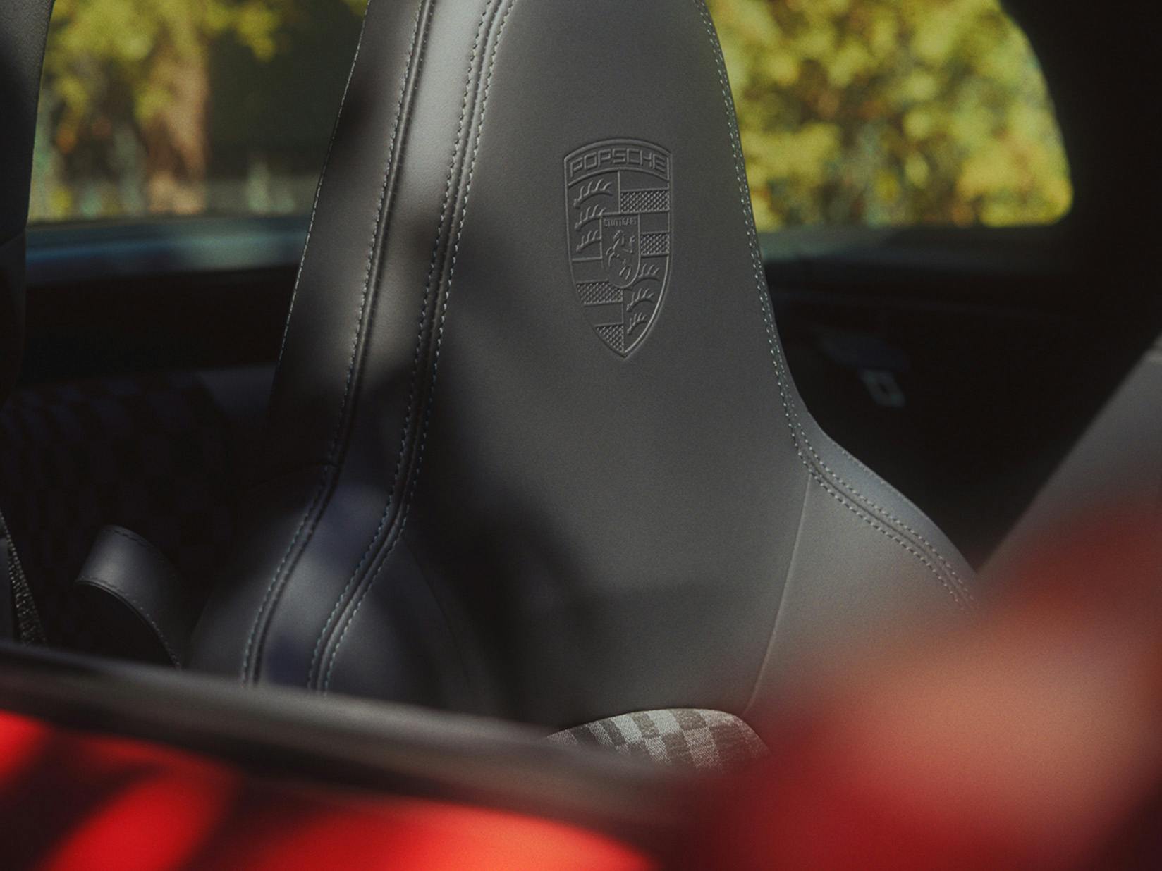 Detailed view of the headrest of a Porsche seat with the Porsche Crest embossed on it.
