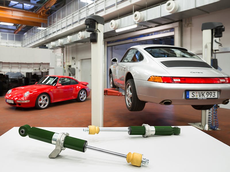 Detail shots: two single-tube gas pressure shock absorbers, two Porsche 993s in the workshop.