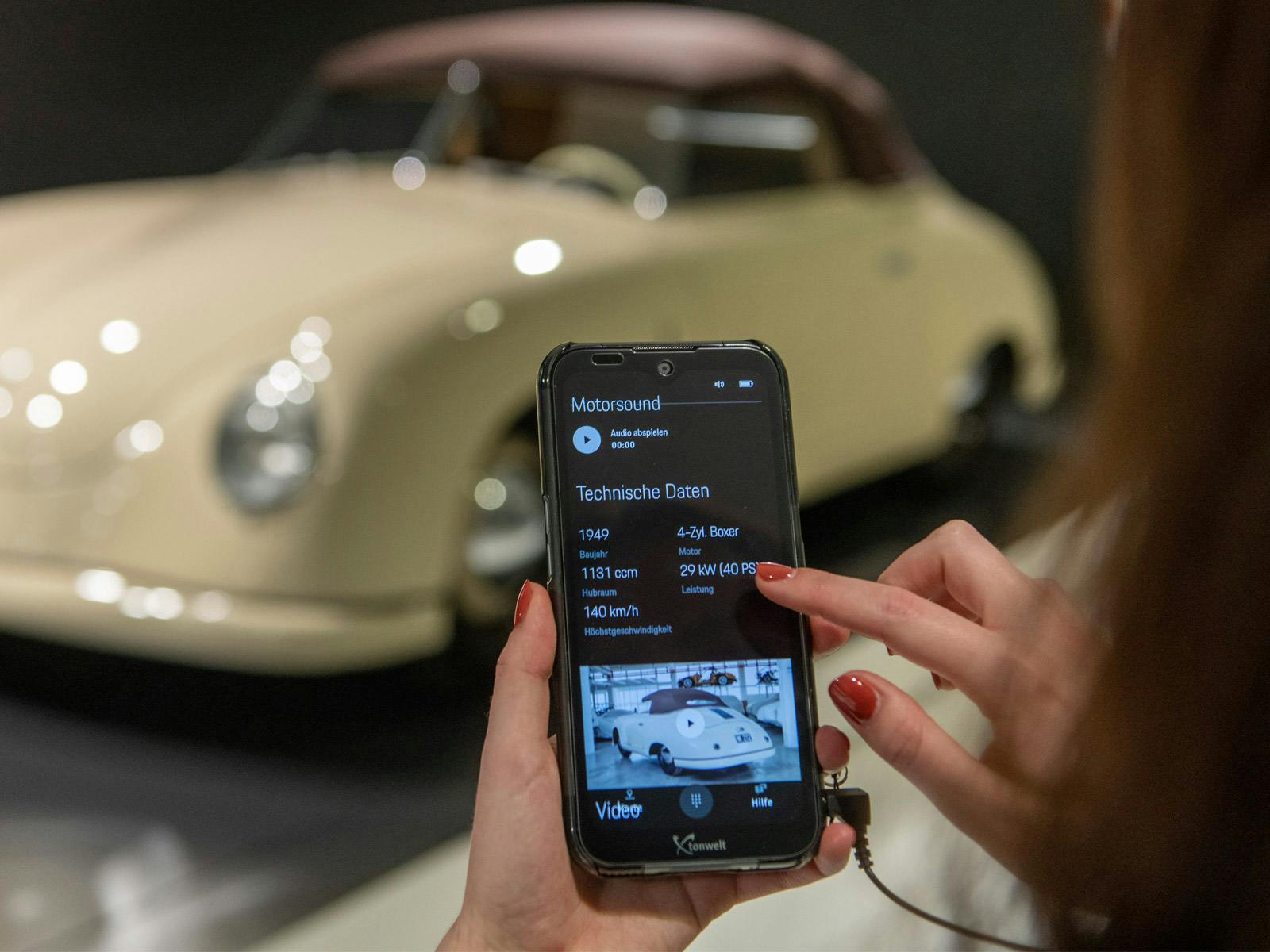 Eine Besucherin des Porsche Museums die auf ihrem Smartphone technische Daten im Multimedia Guide anschaut