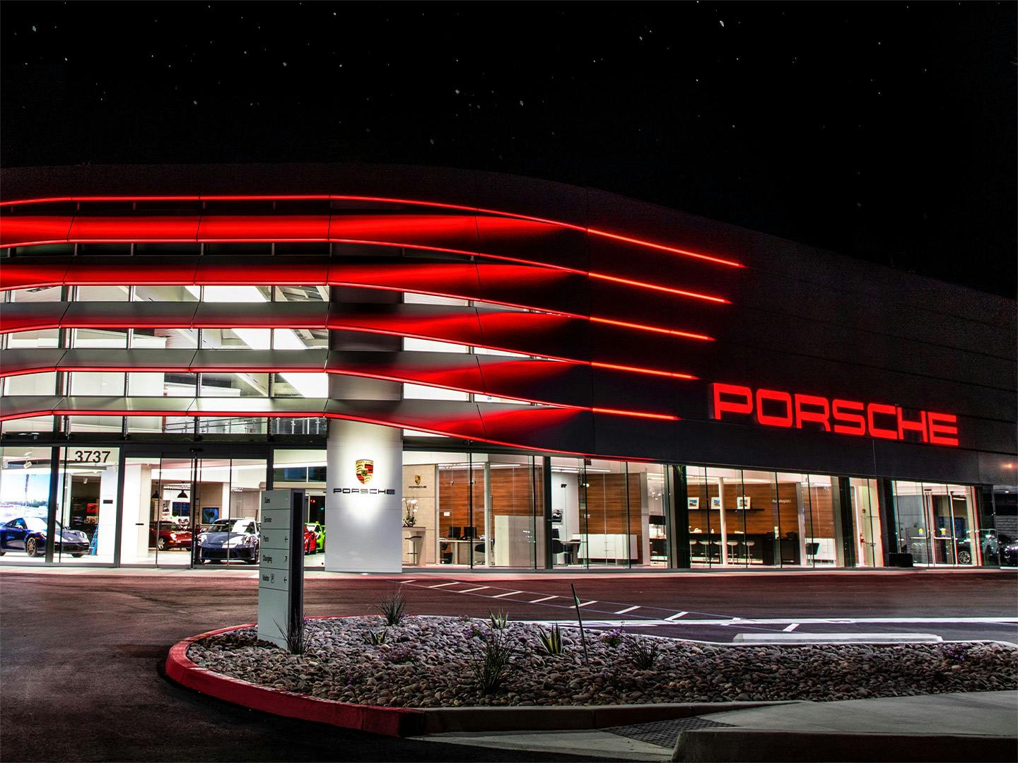 L'ingresso principale del Centro Porsche di notte con la moderna illuminazione esterna rossa.