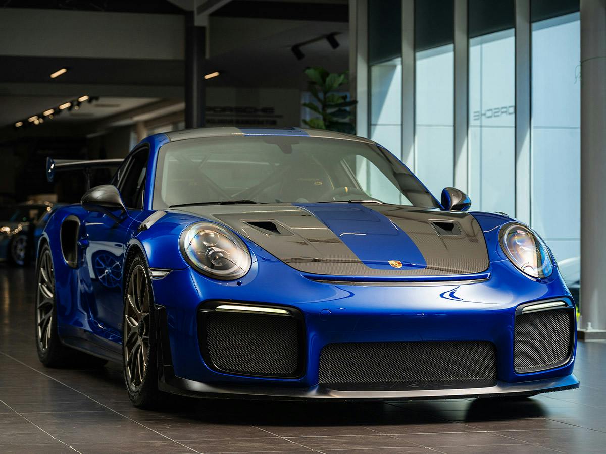 Front view of the Porsche 911 GT2 RS in Paint to Sample Aquabluemetallic with carbon exterior details, photographed indoors.
