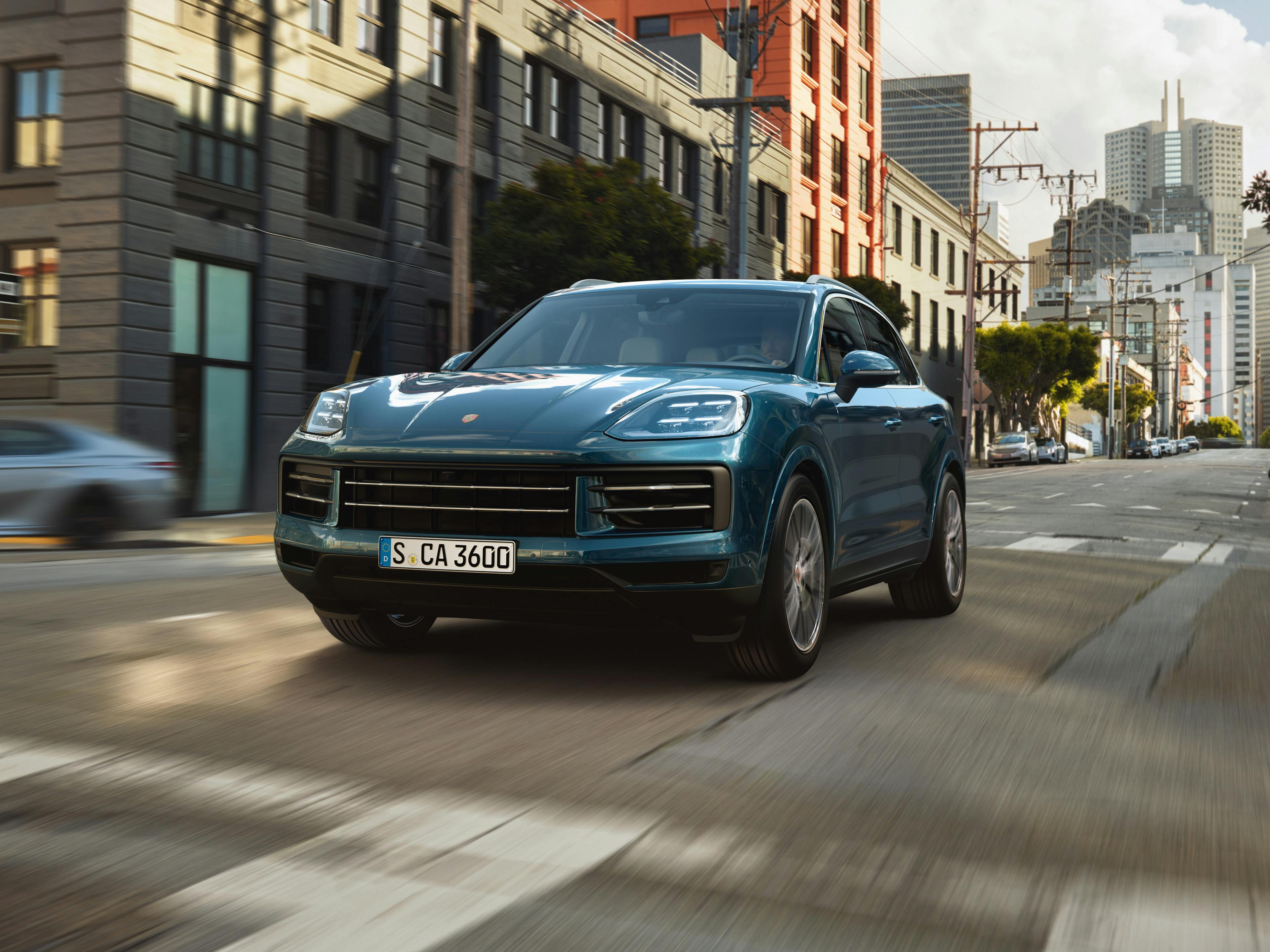 A Porsche Cayenne drives through a city street.