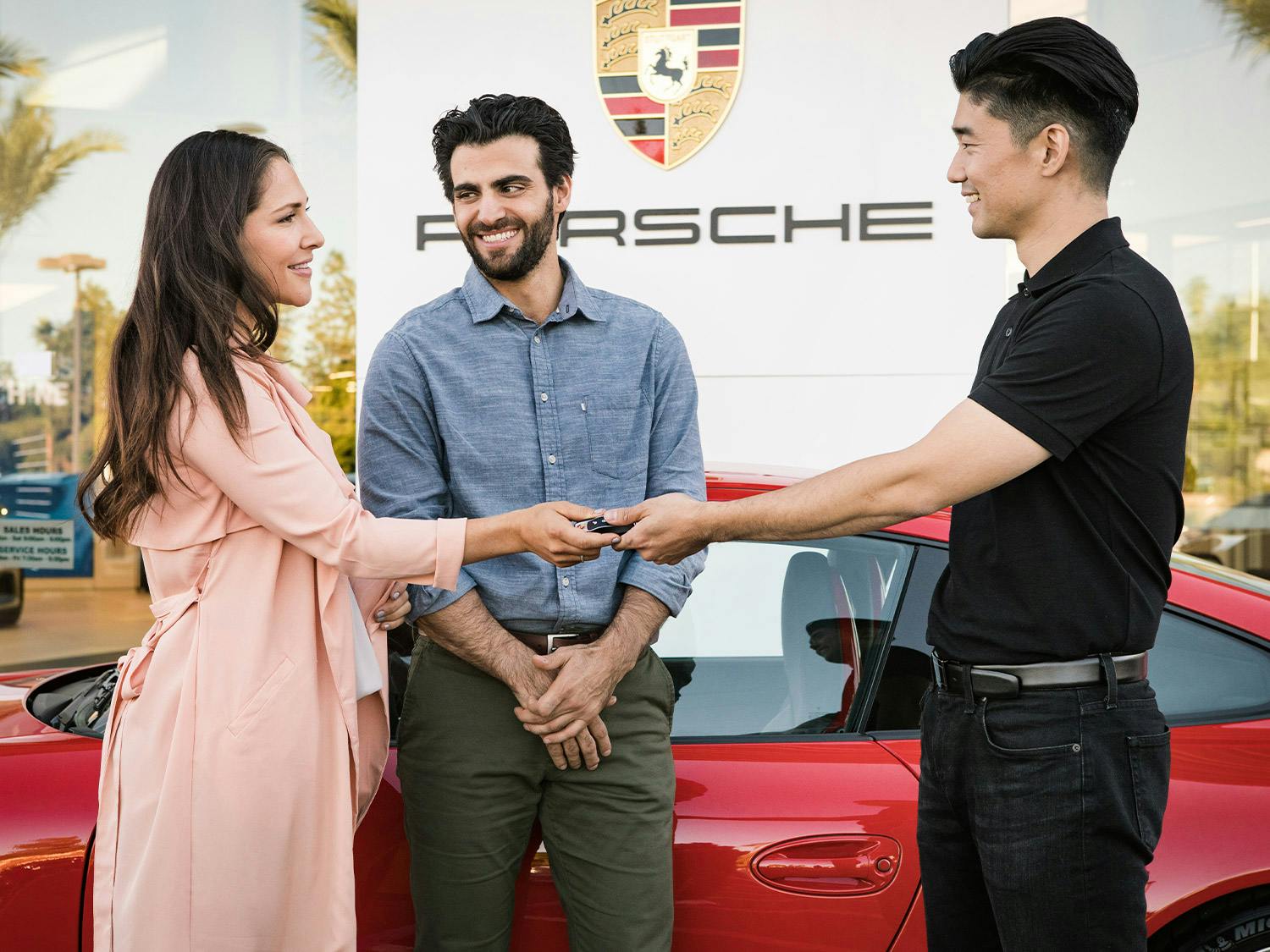 A Porsche employee hands the keys to a couple.
