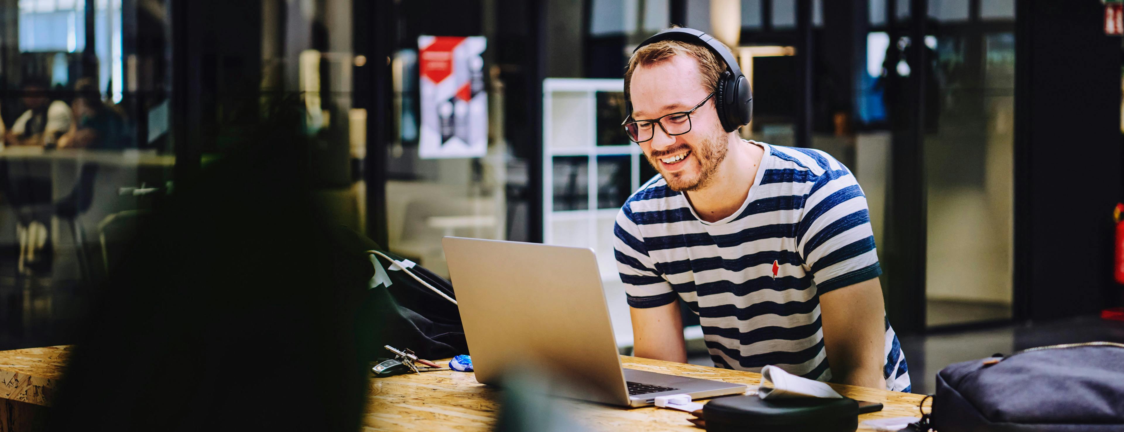An intern at Porsche stands  on a scooter and smiles at the camera.