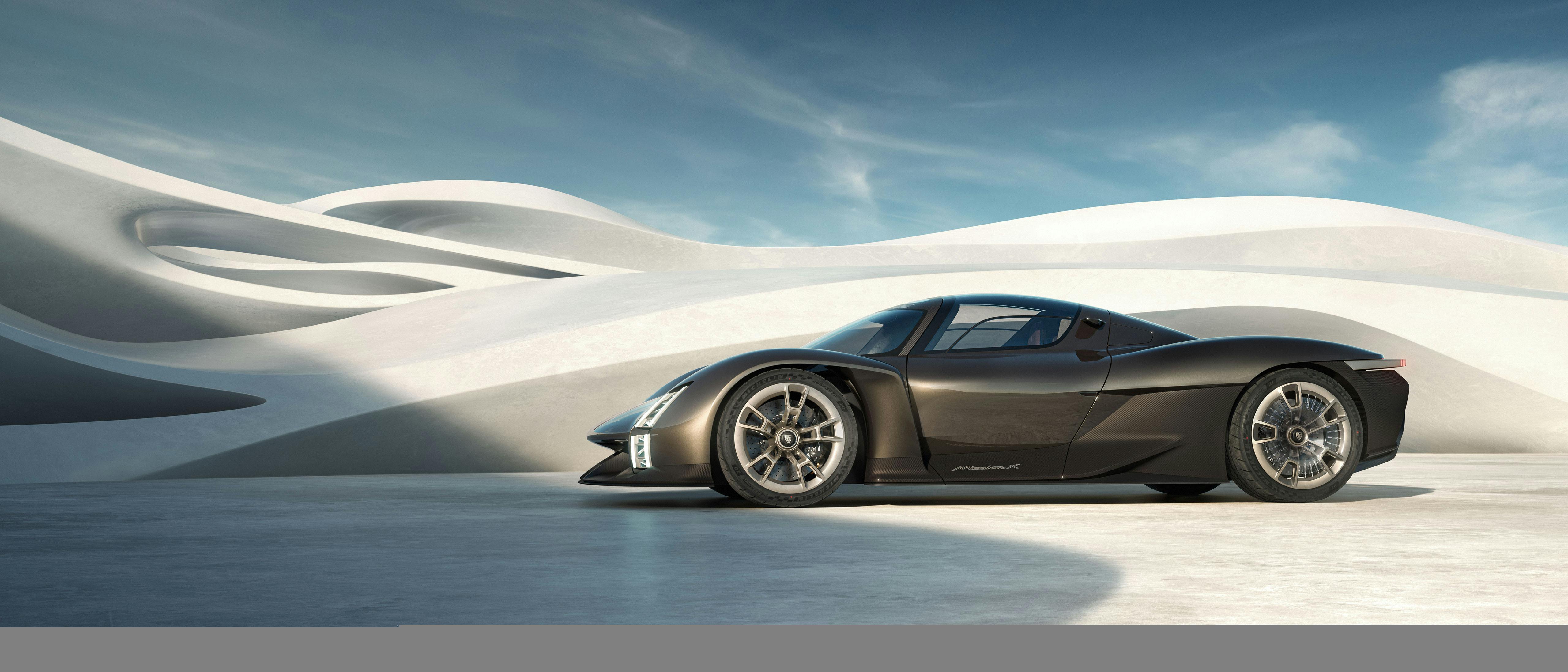 La Porsche Mission X in Rocket Metallic davanti a un edificio ondulato. Concept della vettura di lato, visibile di profilo.