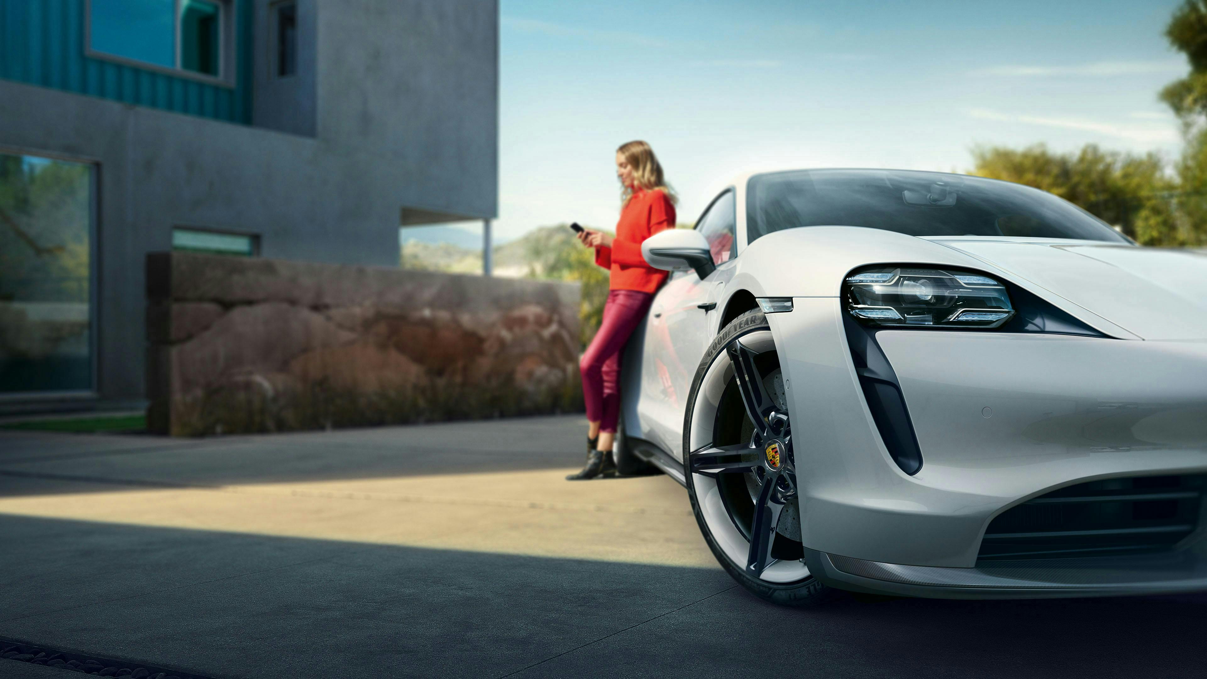 Porsche Taycan Turbo S tyre in the foreground with a woman holding a phone in the background.