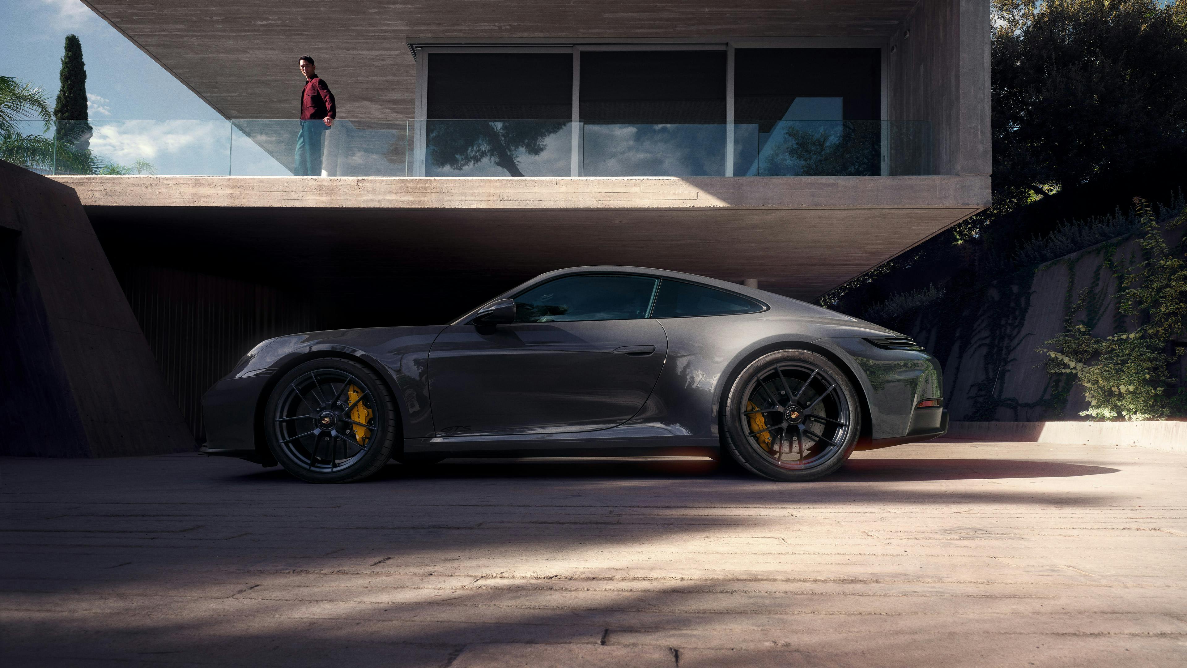 Porsche sports car in front of modern building, side view.
