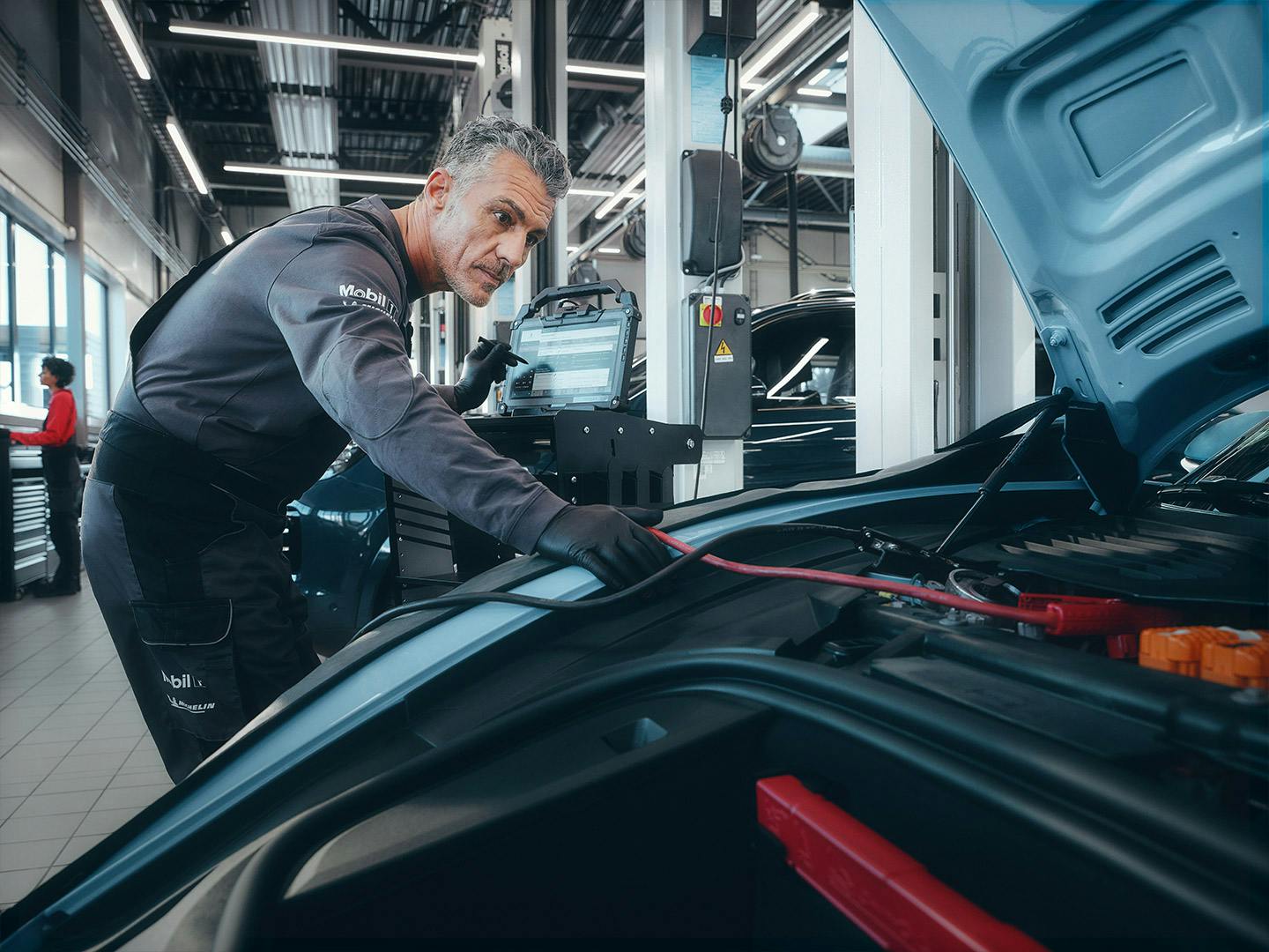 A workshop employee leans over the open bonnet of the Taycan.