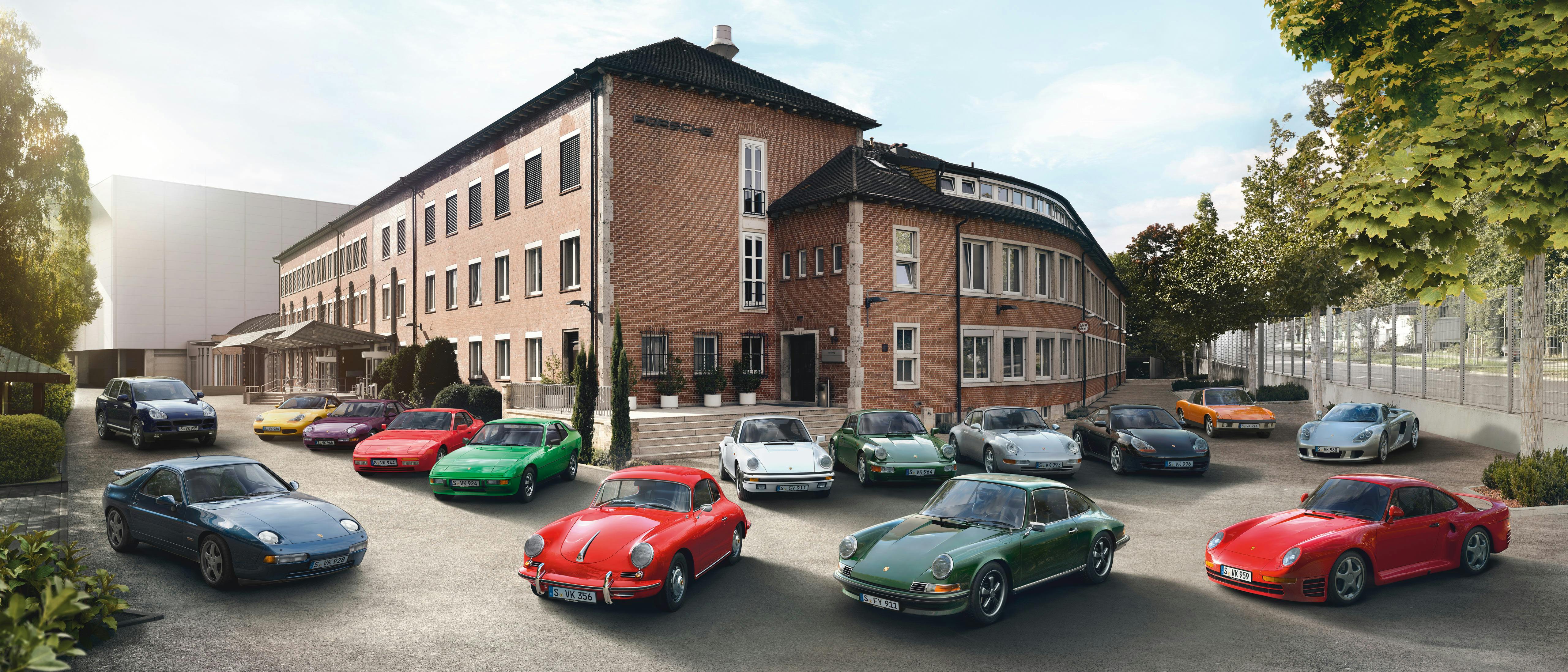 Verschiedene Porsche Fahrzeuge in verschiedenen Farben stehen vor einem Backsteingebäude.