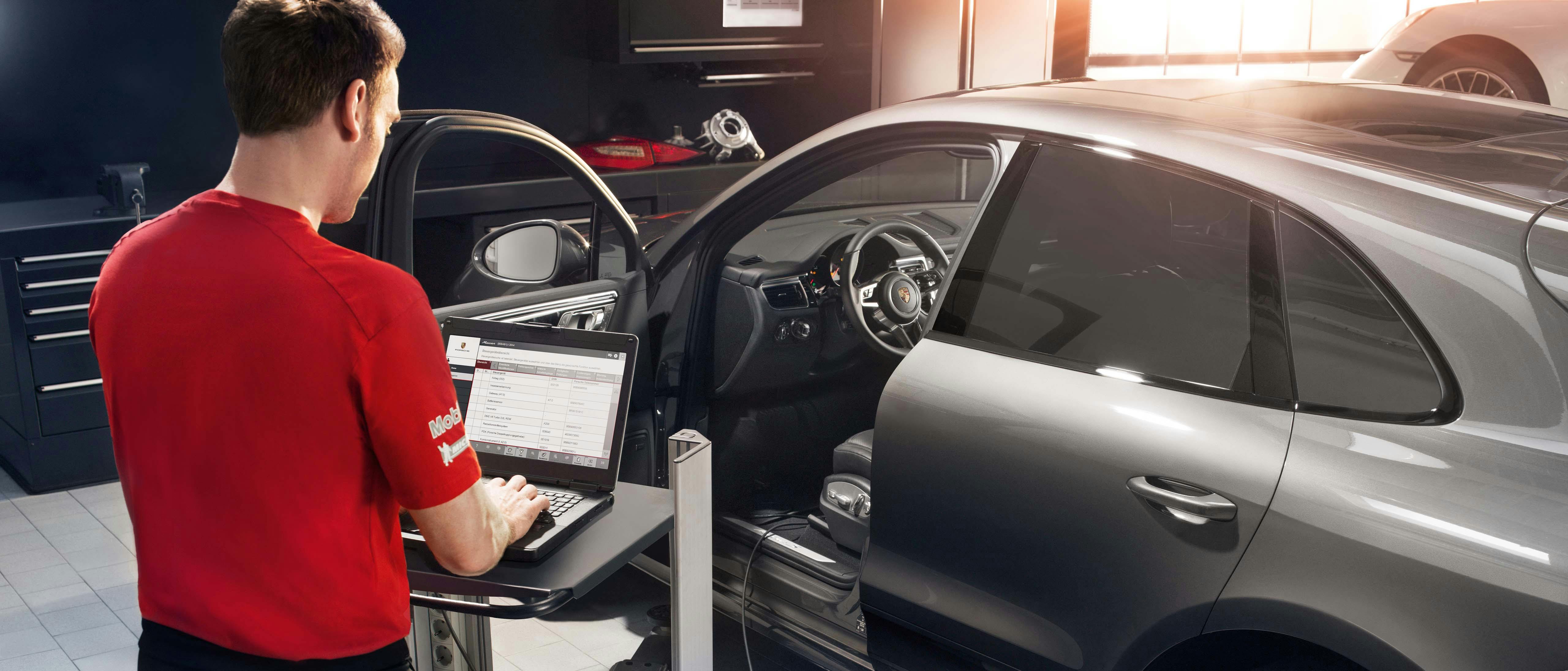 Man in red shirt working on a silver car