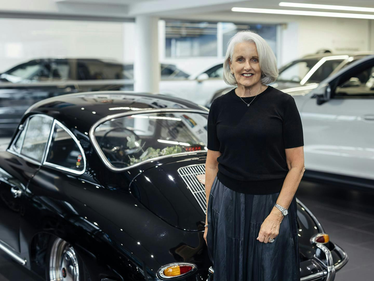Deb Simpson stands in front of her newly restored black Porsche 356.