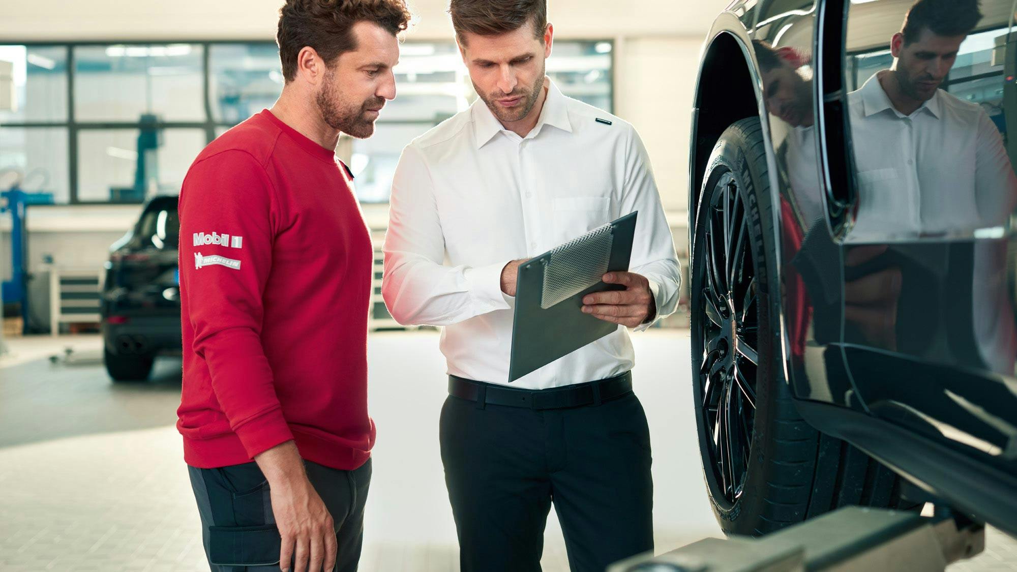 A Porsche mechanic and engineer checking vehicle documentation.