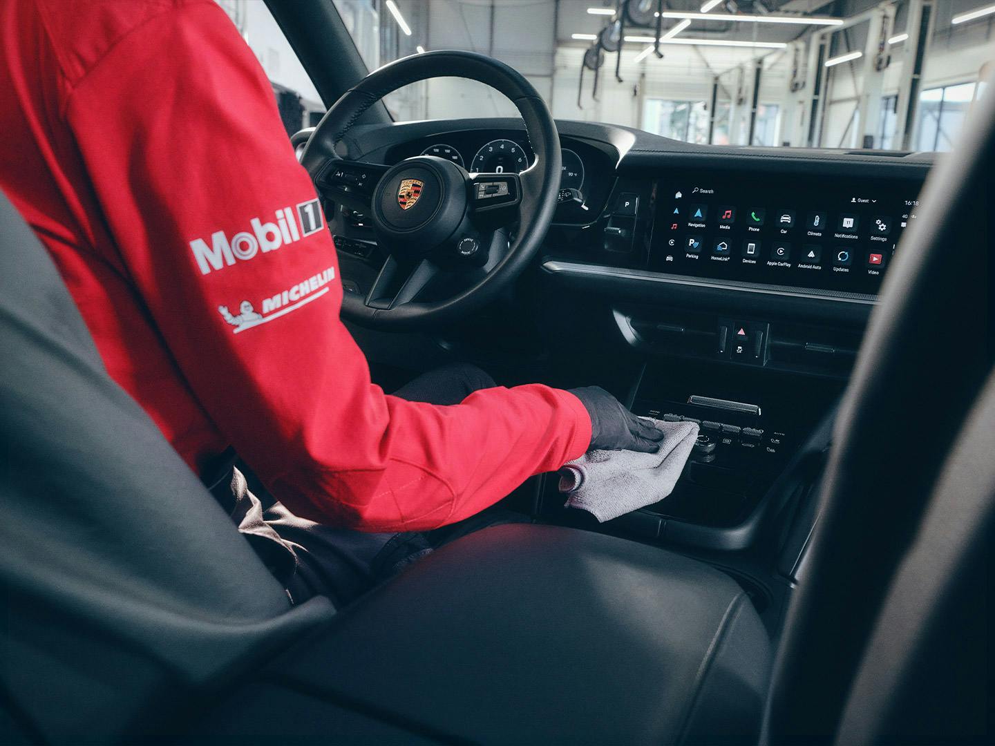 Ein Porsche-Mitarbeiter reinigt das Armaturenbrett eines Porsche mit einem Tuch.