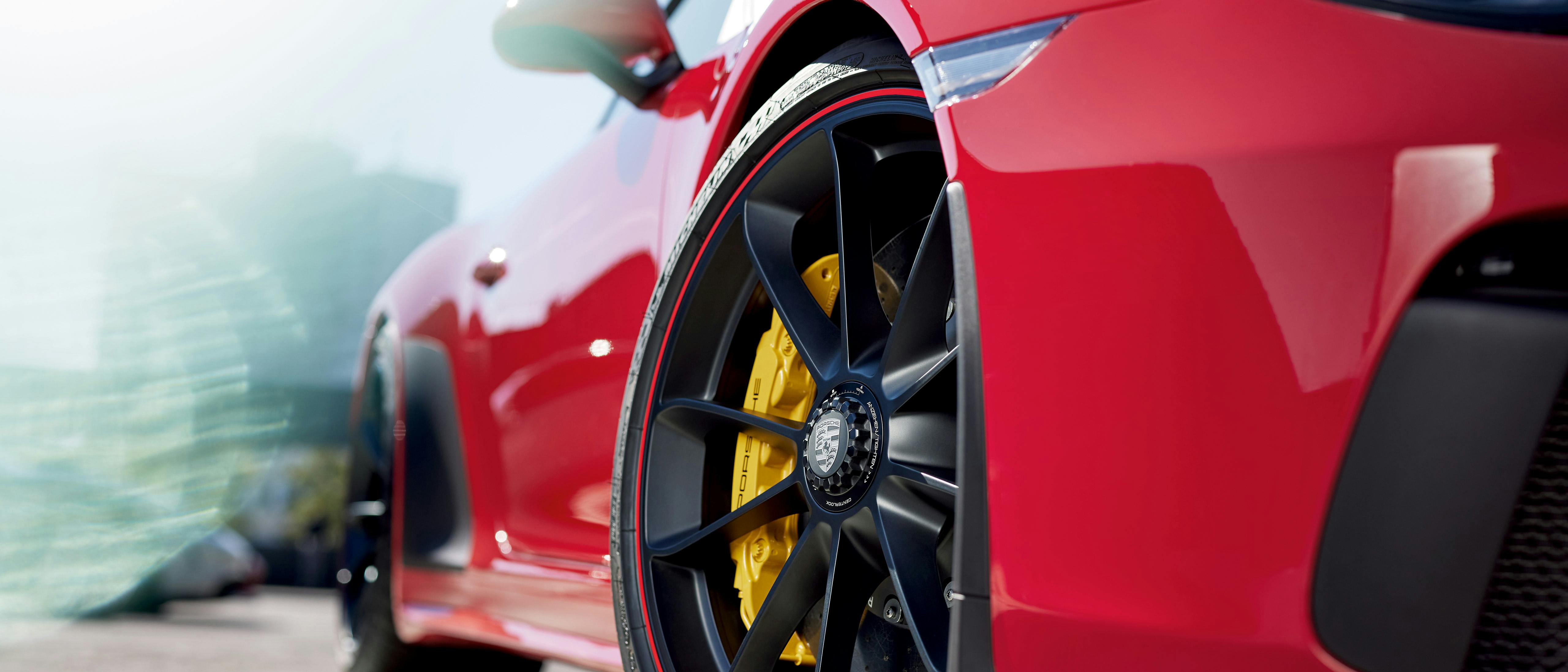 Roter Sportwagen, Nahaufnahme des vorderen linken Rads mit gelben Bremssätteln und schwarzen Felgen.