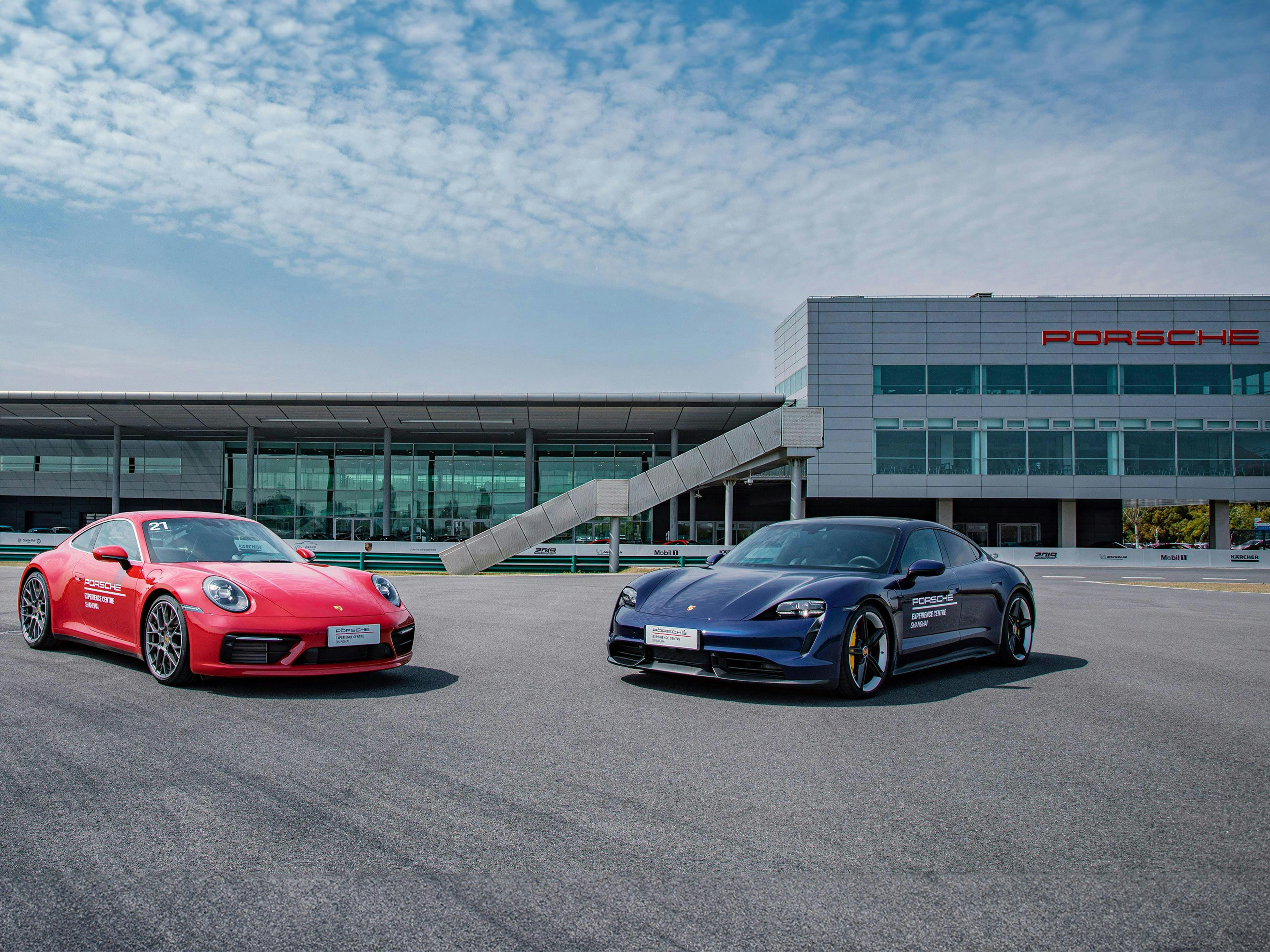 Frente al Porsche Experience Center de Shanghái se encuentran dos vehículos Porsche, frente a frente.