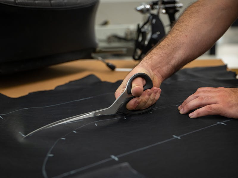 Employee of the factory restoration Atlanta cutting fabric with scissors.