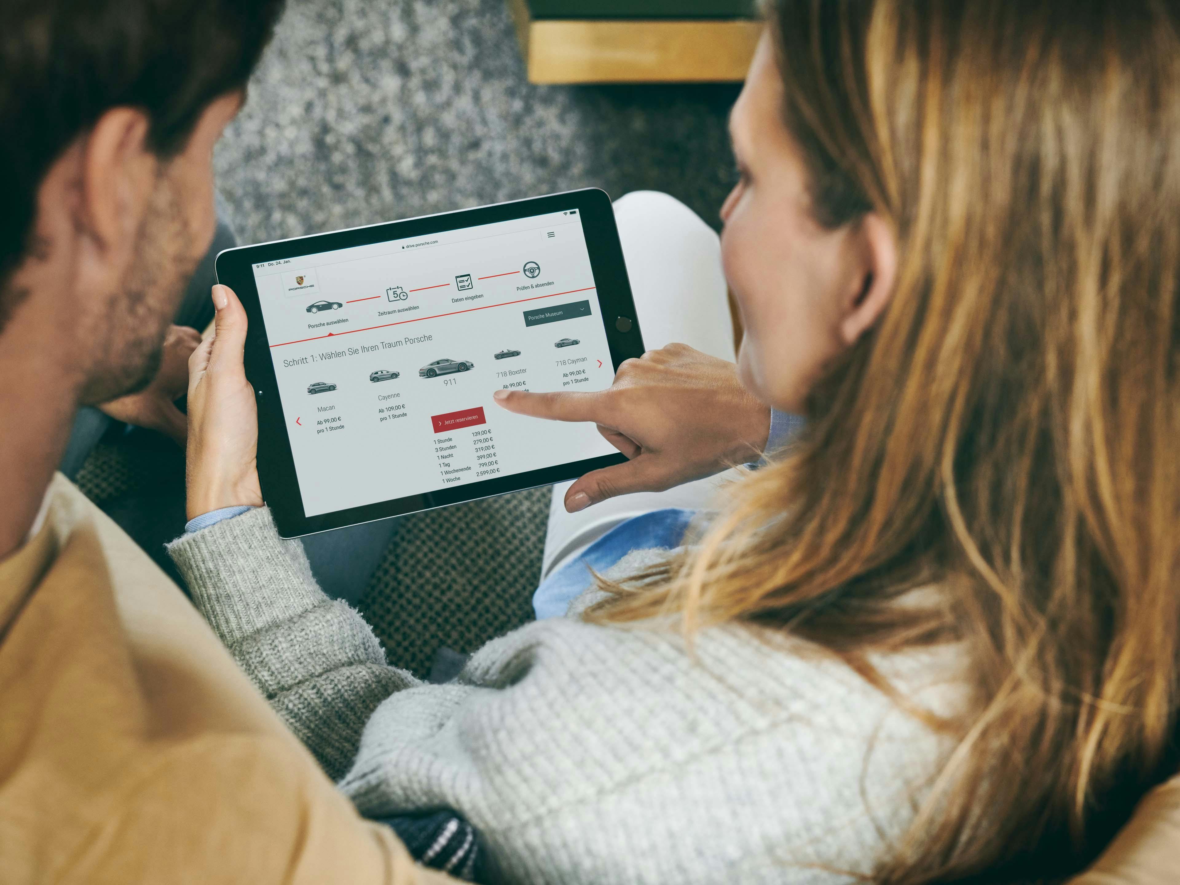 Couple en train de parcourir les options Porsche sur une tablette.