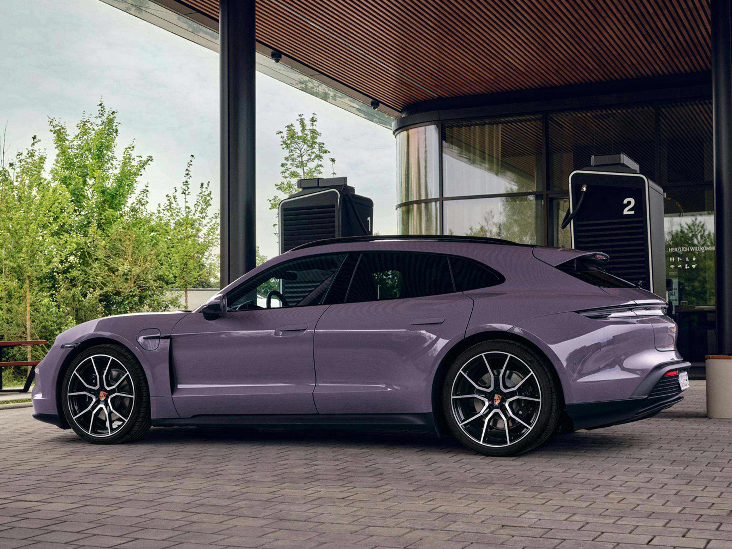 Porsche Taycan Sport Turismo ładujące się w Porsche Charging Lounge. Widok samochodu z boku.