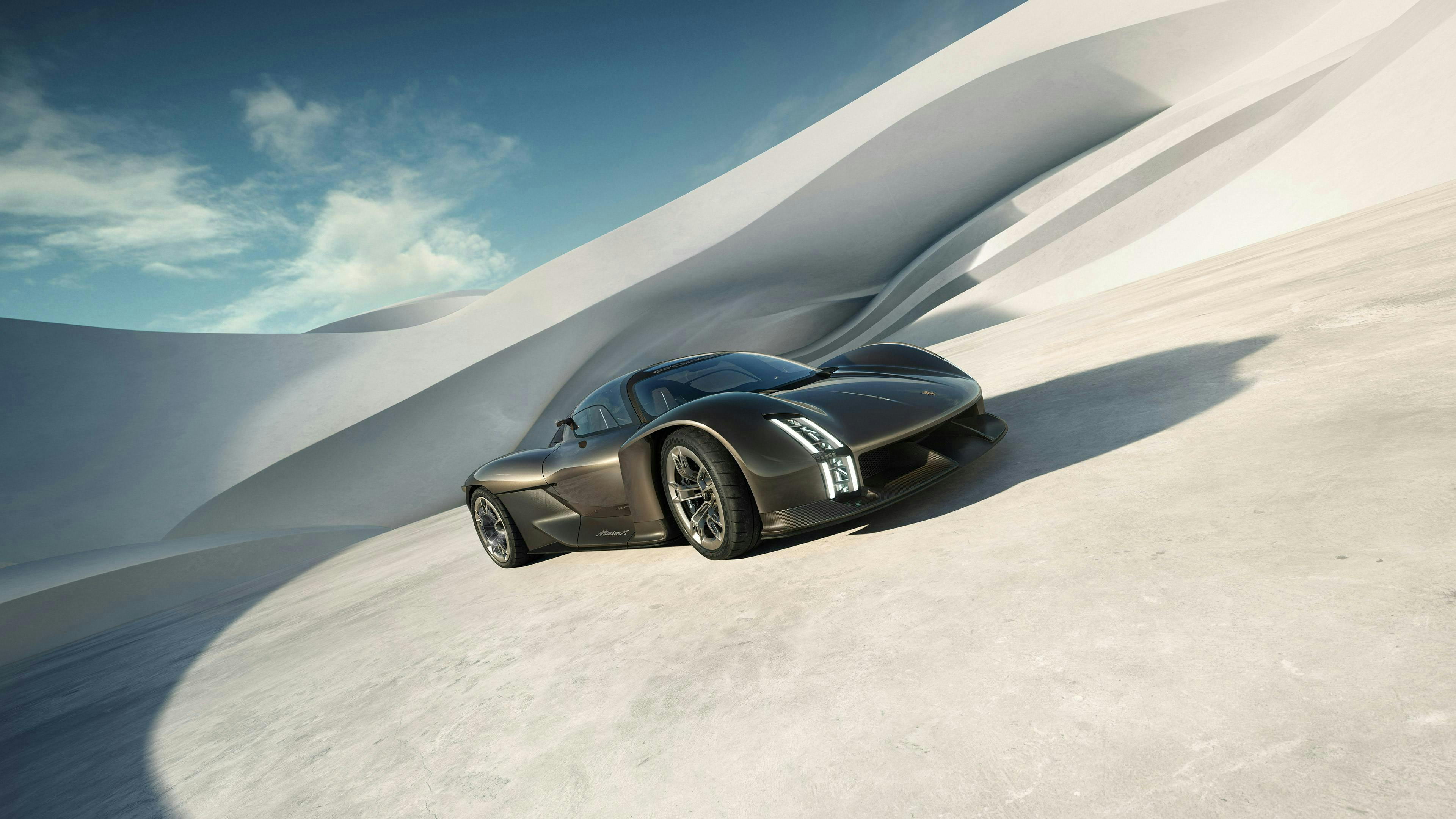 波のような建築物の前に停まっているロケットメタリックのPorsche Mission X フロントビューとサイドビュー