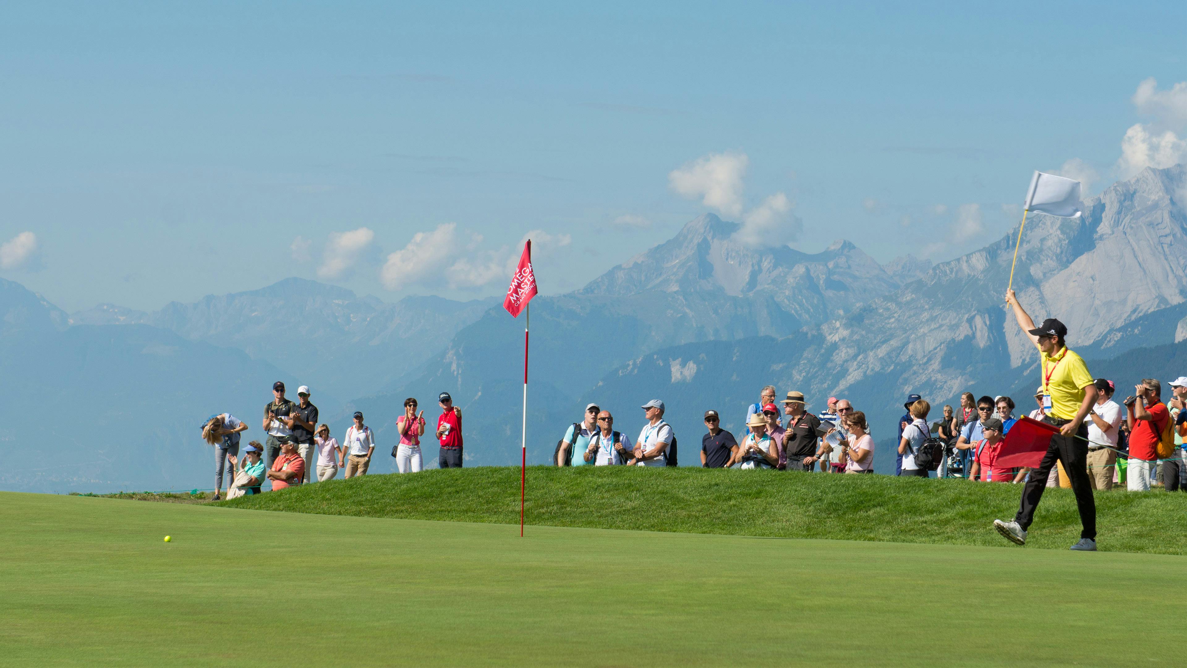 Ein Helfer hält eine weiße Fahne in die Luft, in Crans-Montana mit den Alpen im Hintergrund