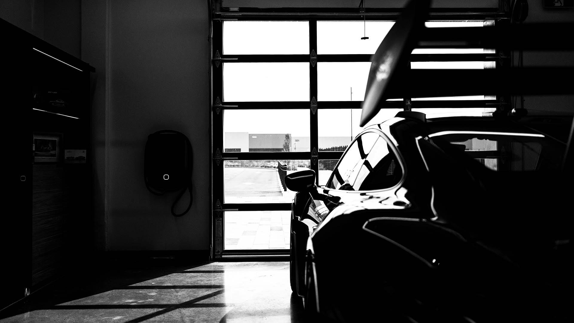 Une photo en noir et blanc d'une Porsche 911 garée dans un garage moderne. ​