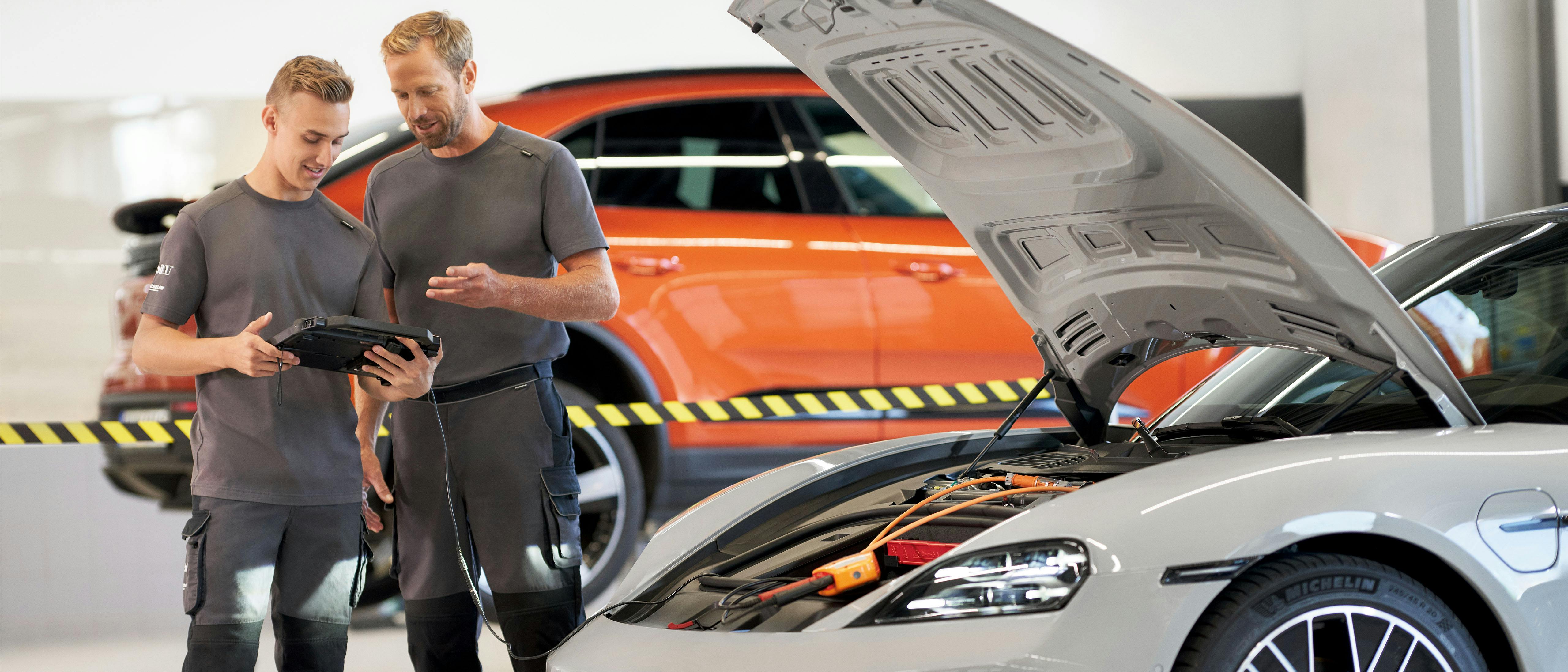 Twee mannen staan in een werkplaats bij een Porsche Taycan
