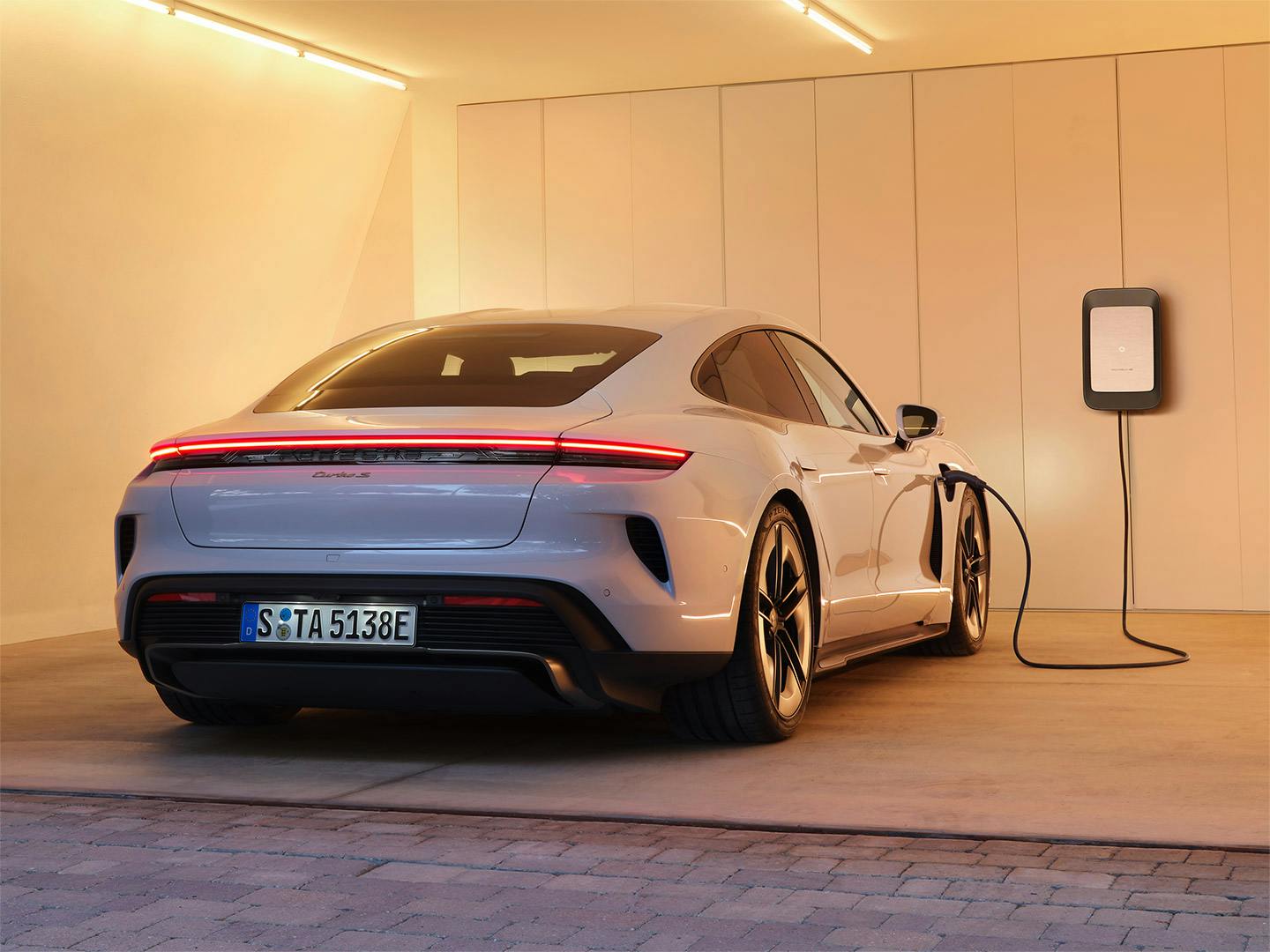 A white Porsche Taycan inside of the garage of a modern home.
