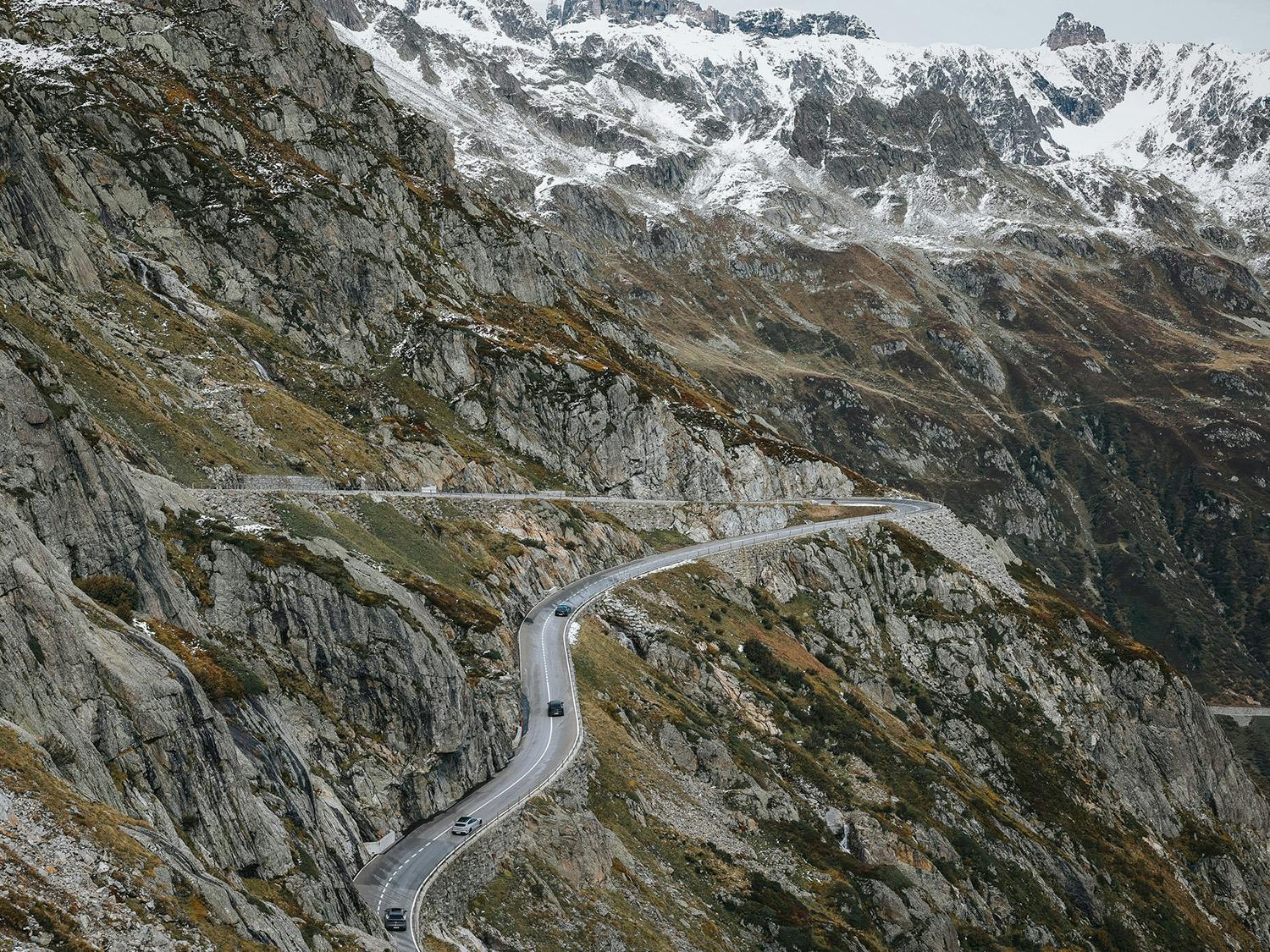 A wide shot of Porsches on a winding mountain road.