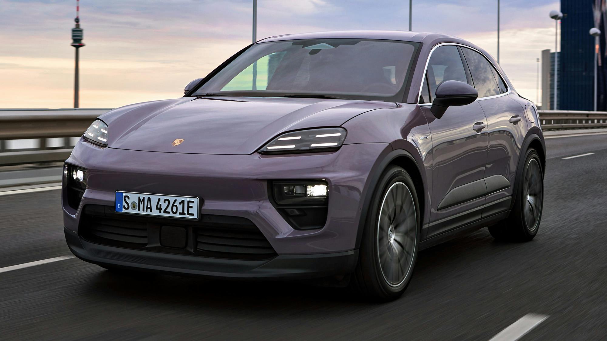 Un Porsche Macan 4 en color Violeta circula por una autopista al atardecer.
