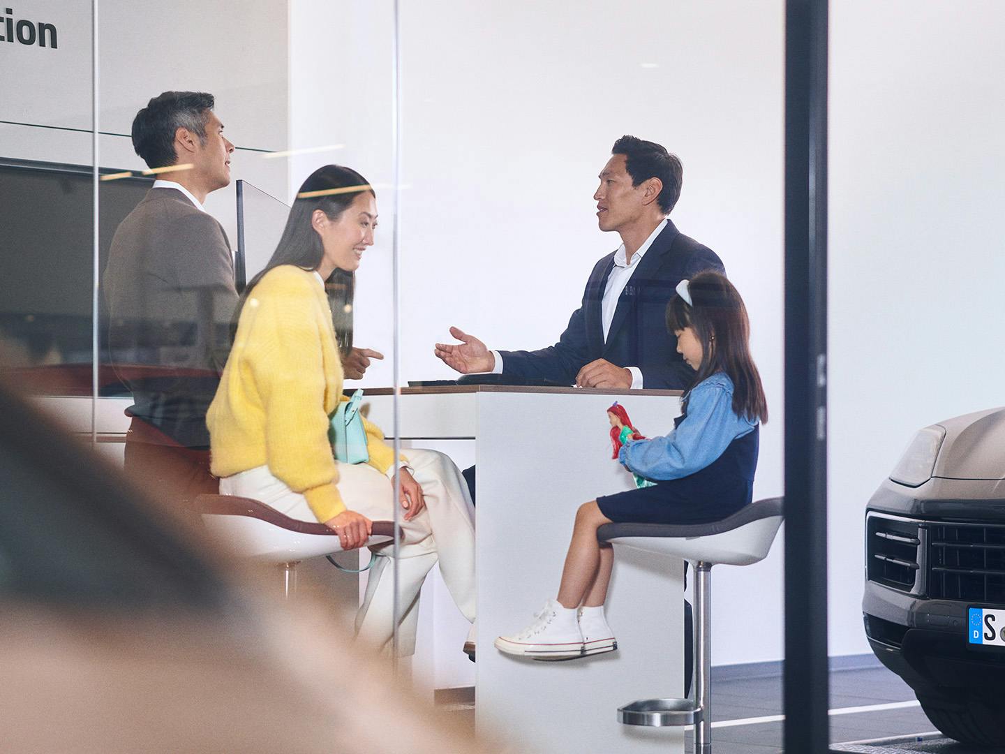 A family of three talking to the Porsche consultant in a Porsche Service Centre.