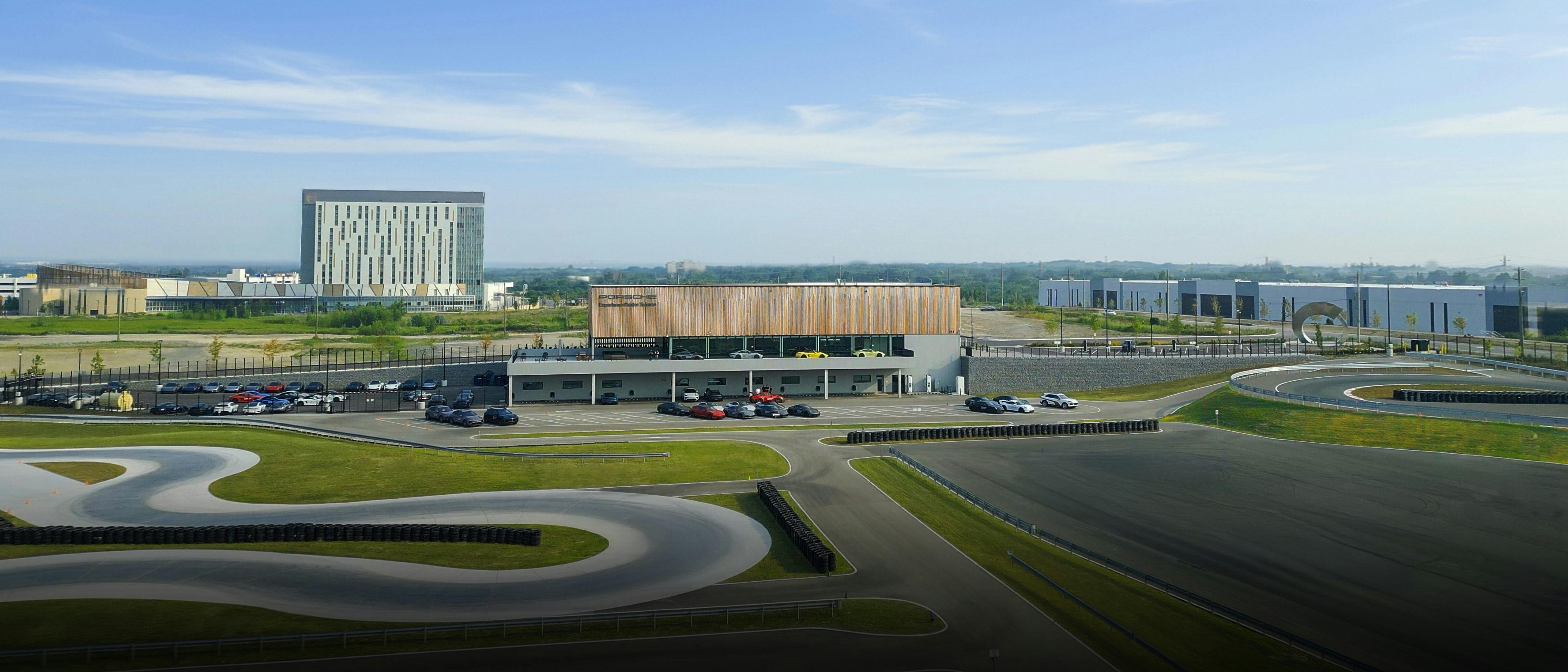 Aerial view of Porsche Experience Centre Toronto, with a modern building in the back surrounded by a driving track.
