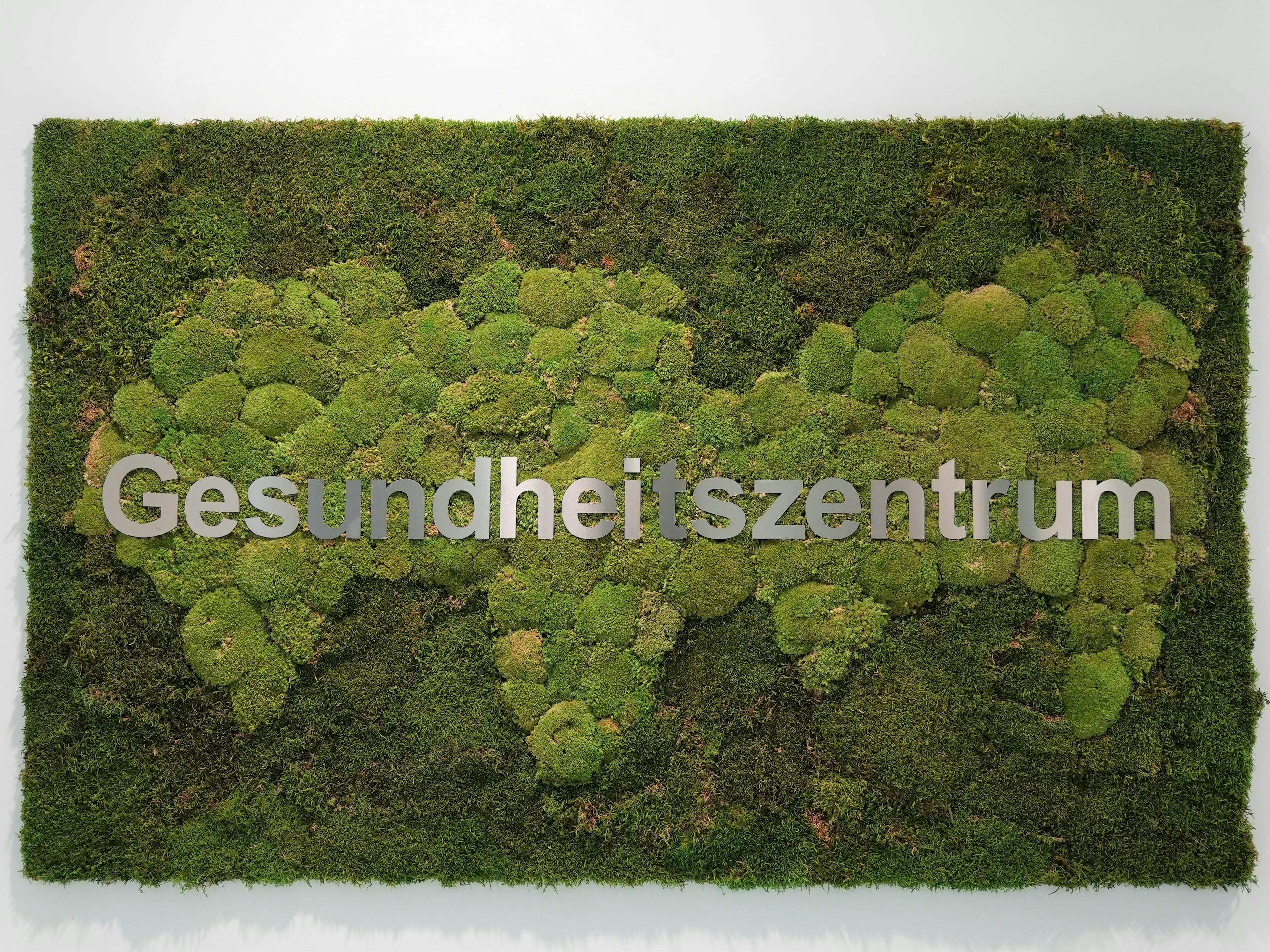 Ein Bild aus Moos und Gras mit dem Schriftzug Gesundheitszentrum.