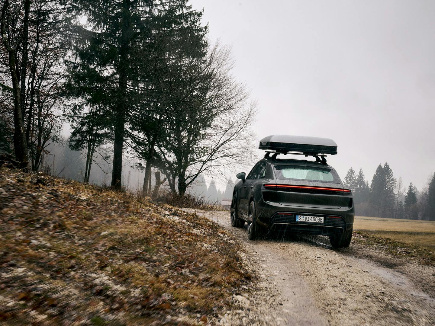 Een Porsche Macan rijdt door de bergen met een daktent