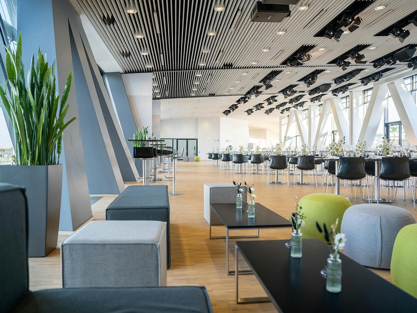 Die Eventebene des Porsche Museum ist für ein Event dekoriert. Bestehend aus Loungemöbeln, Stehtischen und gedeckten Tischen.