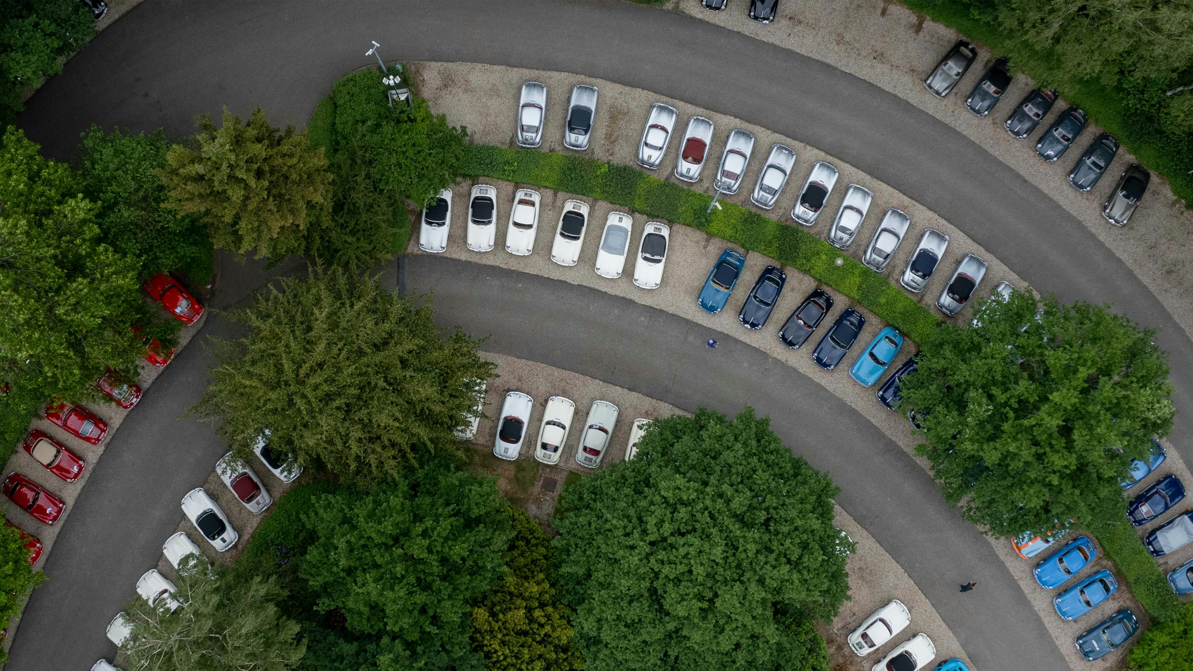 Bovenaanzicht van veel Porsche modellen naast elkaar geparkeerd.