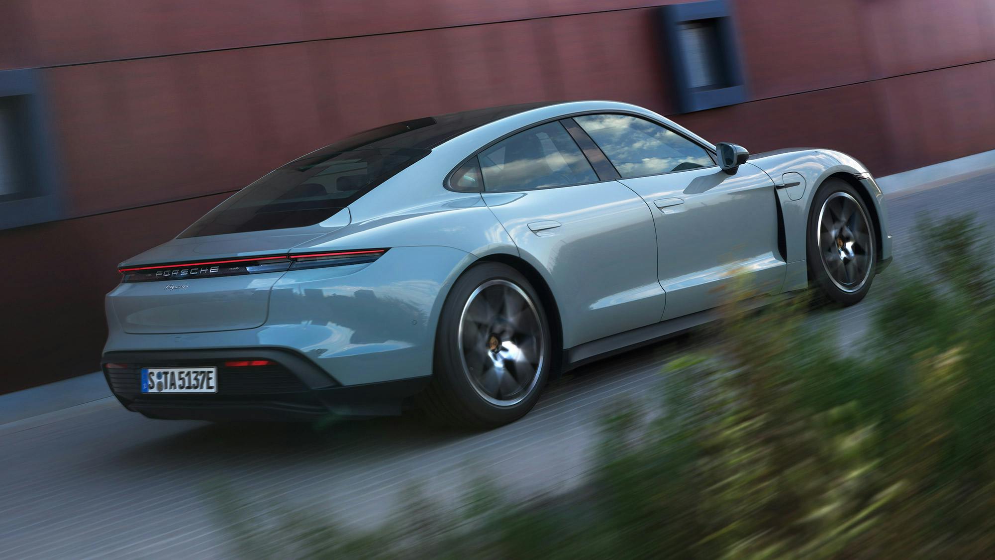 Eine Mutter mit einem Kind auf dem Rücken öffnet die Vordertür des Porsche Taycan.