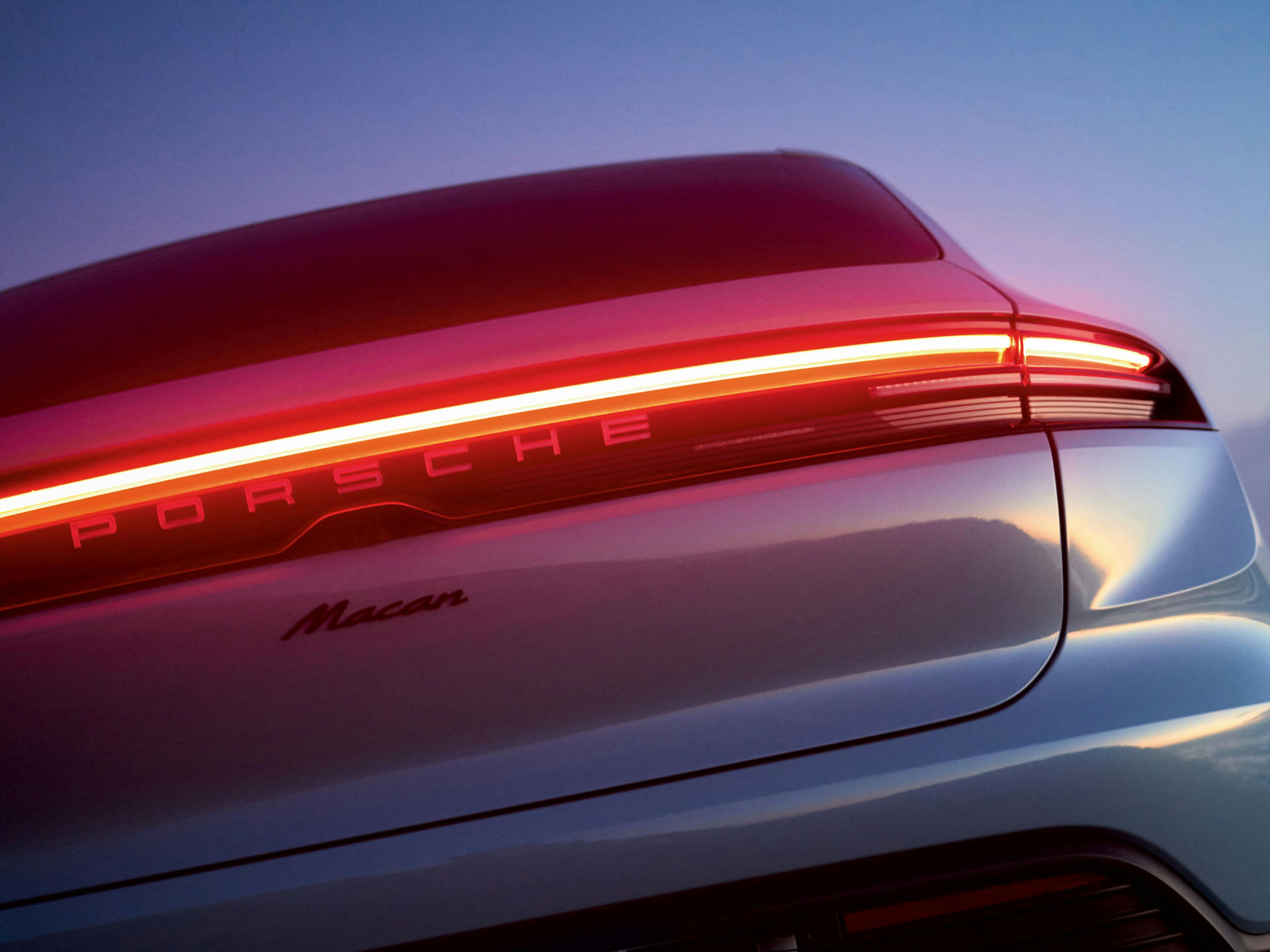 Rear of blue Porsche Macan Electric at dusk.