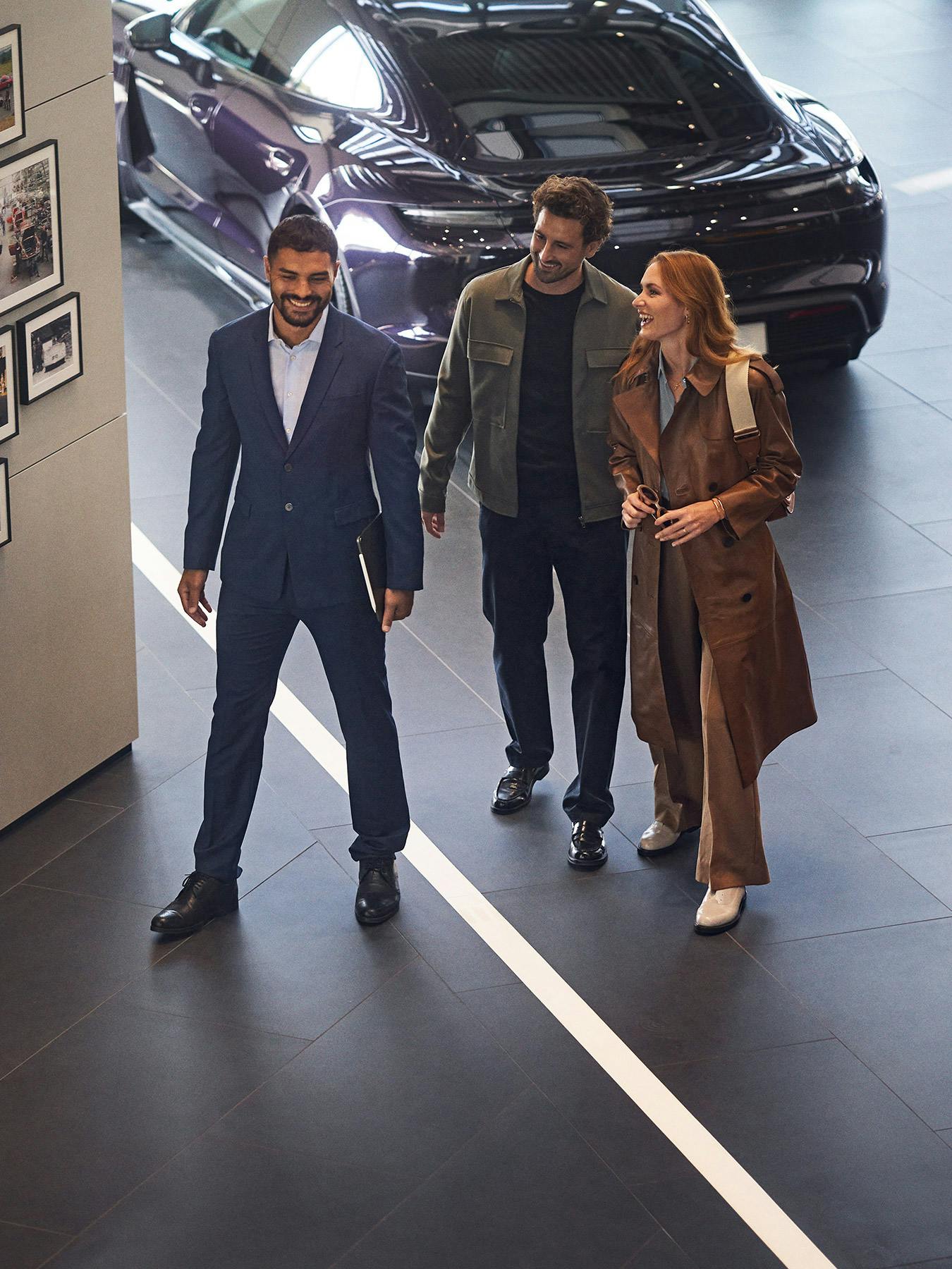 Un employé de Porsche discute avec deux clients dans un centre Porsche.