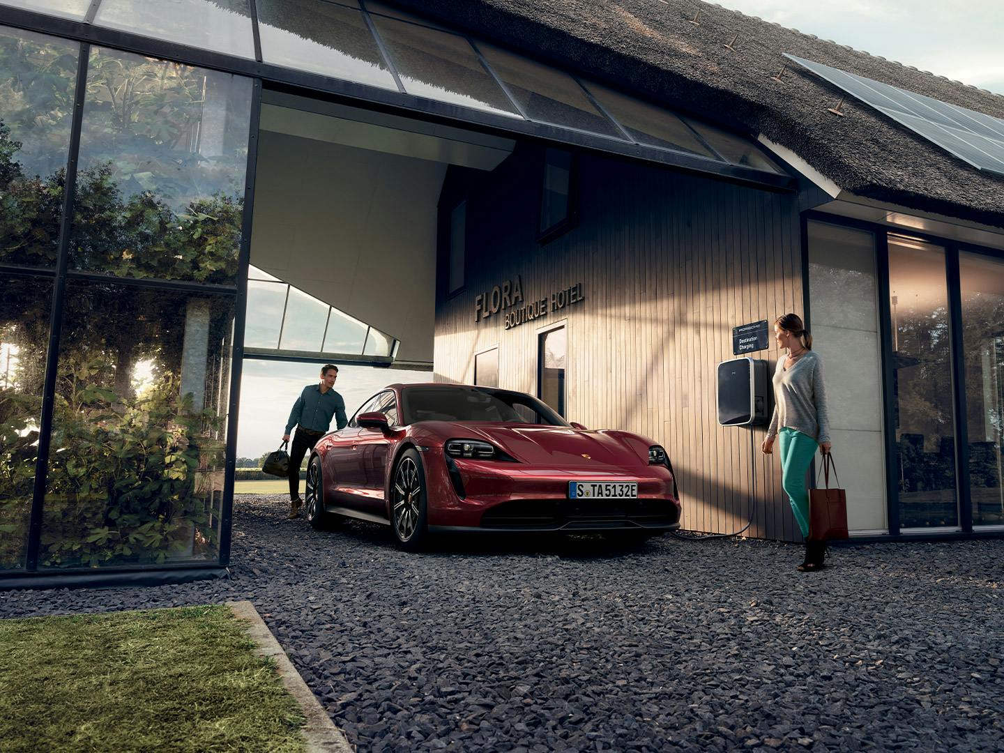 Un uomo si trova accanto al bagagliaio di una Porsche Taycan rossa di fronte al Flora Boutique Hotel.